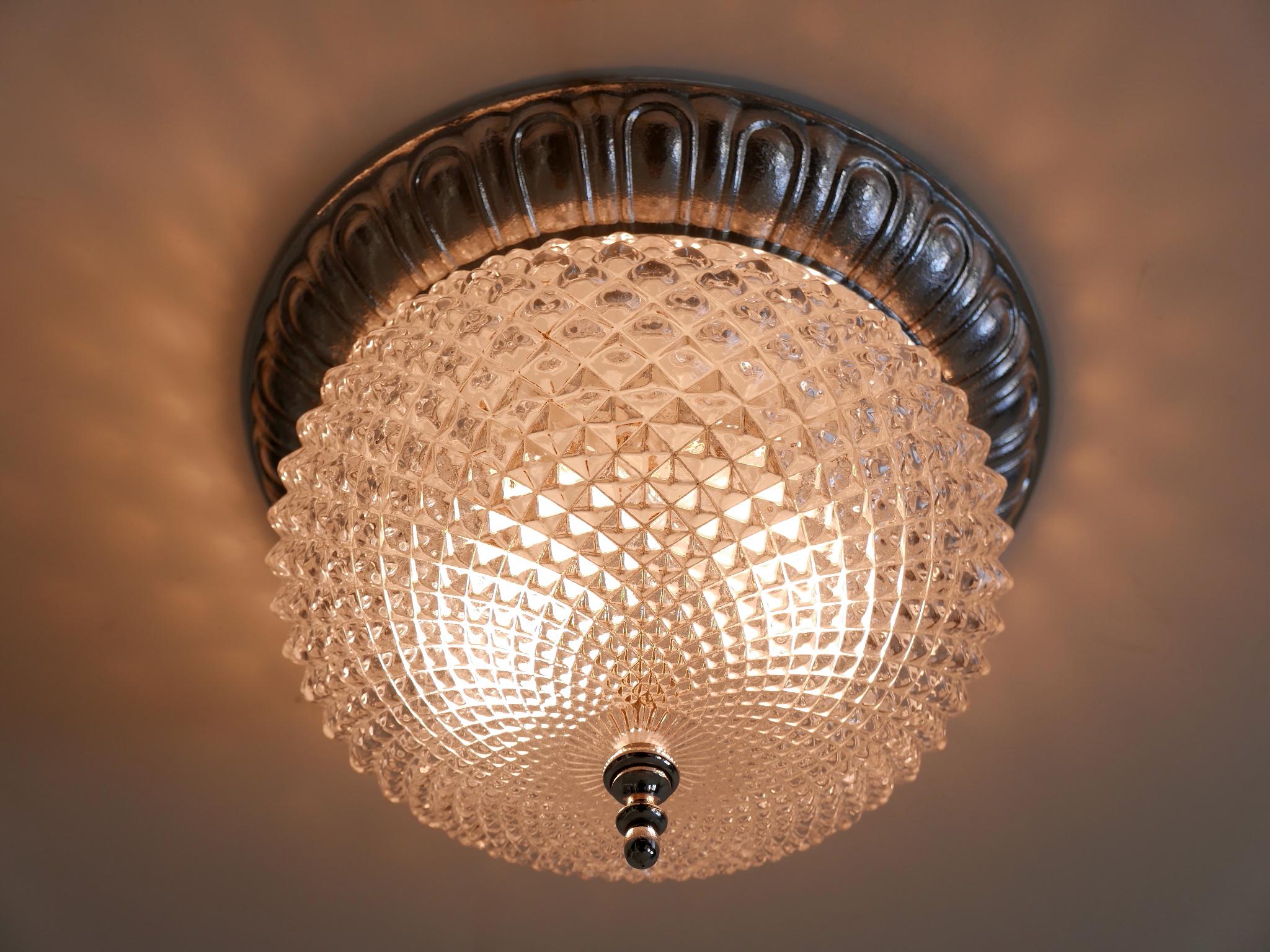 Highly decorative Mid Century Modern ceiling lamp / flush mount. Designed and manufactured by Sölken Leuchten, Germany, 1970s. Manufacturers label at the bottom.

Executed in textured glass and chrome-plated metal, the ceiling fixture has 2 x E14 /