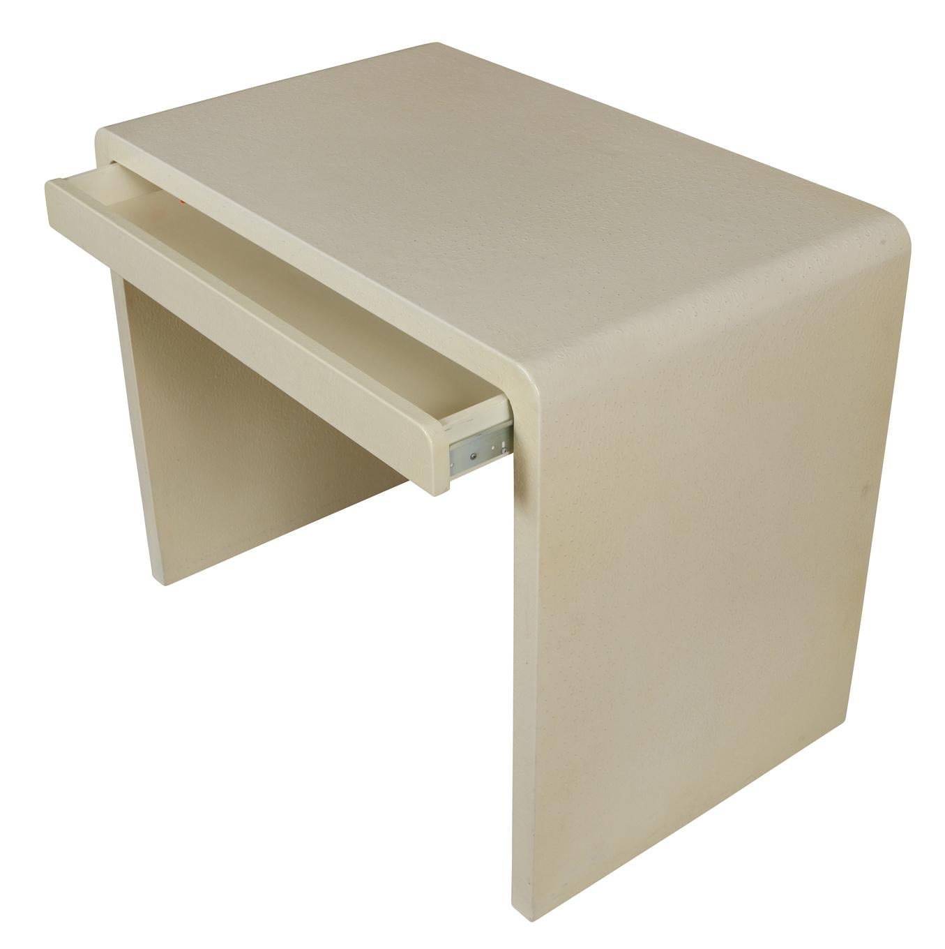 Mid-Century Modern textured and wrapped white leather desk with waterfall edge and one drawer.