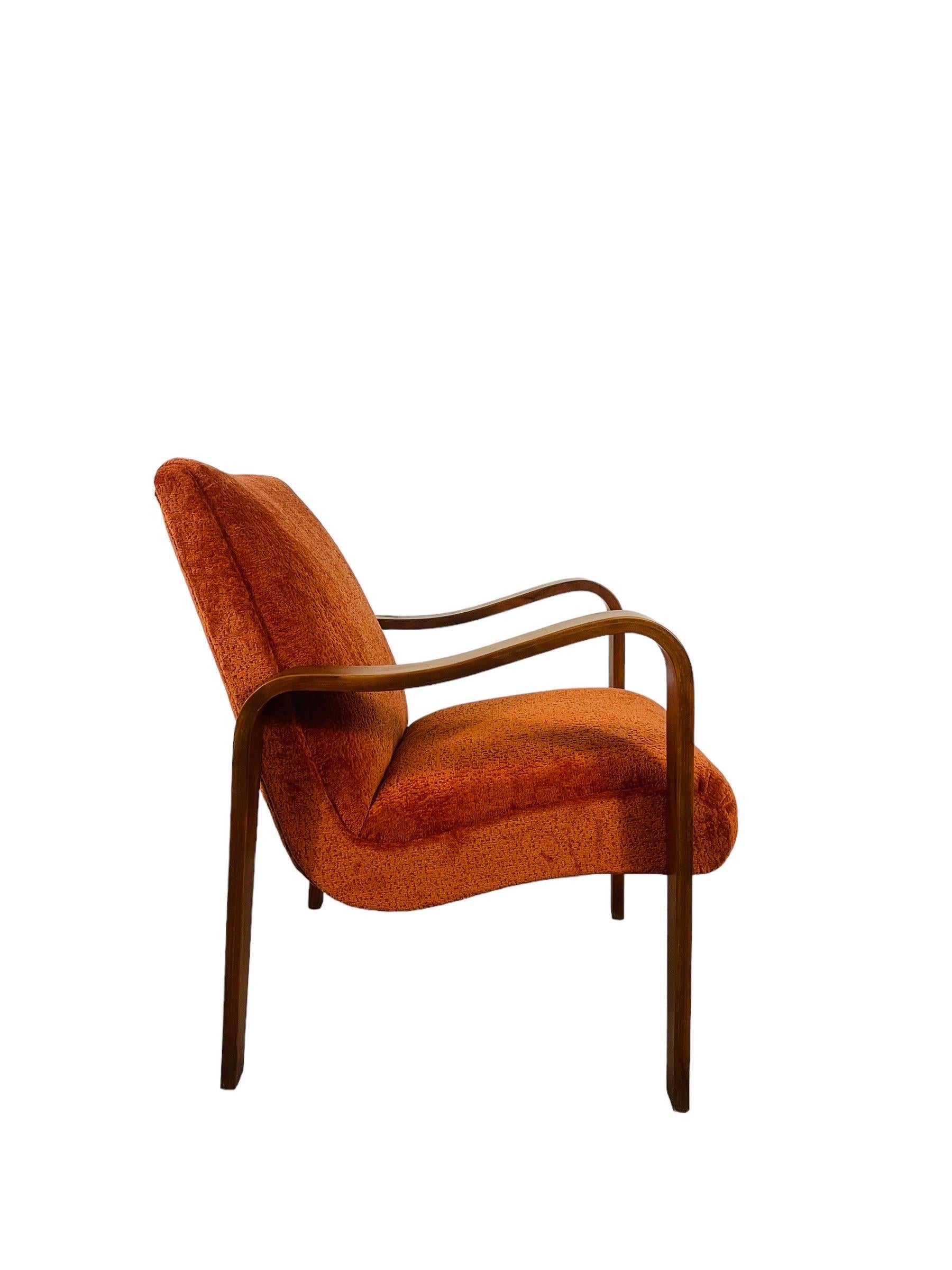 Dive into the vibrant embrace of our reimagined Thonet lounge chair, now dressed in a sumptuous burnt orange fabric that's as inviting as a warm sunset. This Mid Century Modern icon has been lovingly reupholstered to bring a fresh pop of color and
