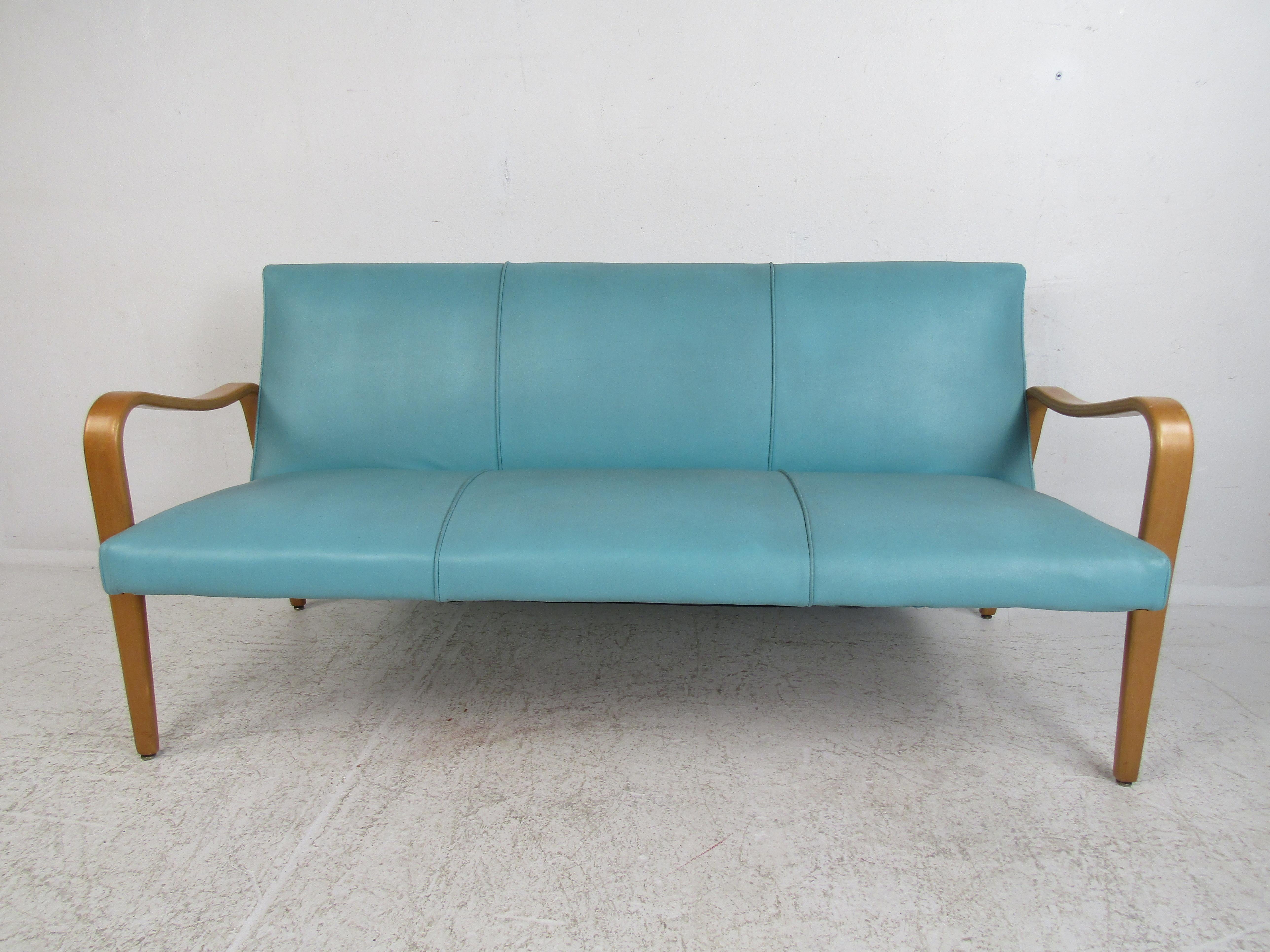 The unique shape of this Thonet style couch features a stylish modern design, eye-catching blue upholstery, and beautiful bentwood armrests. Comfortable seats make this piece a unique addition to any home, business, or office. Please confirm item