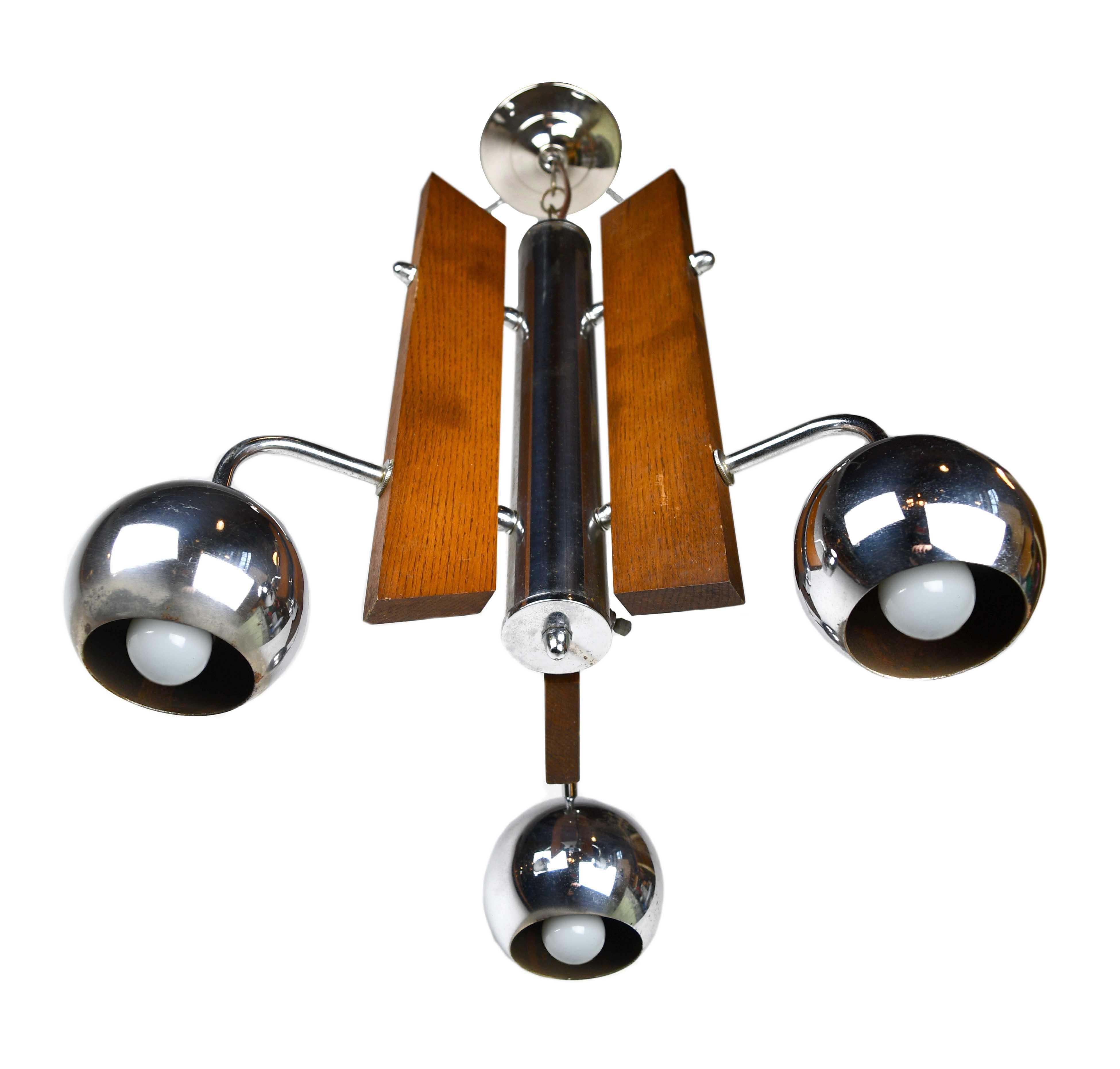 Mid-Century Modern Space Age style chandelier with an interesting mix of wood and chrome, playful in its display of wood grain and shiny surfaces,

circa 1970
Condition: Fair
Finish: Original
Bulb: Medium base S-11 7.5 watts

23 1/2