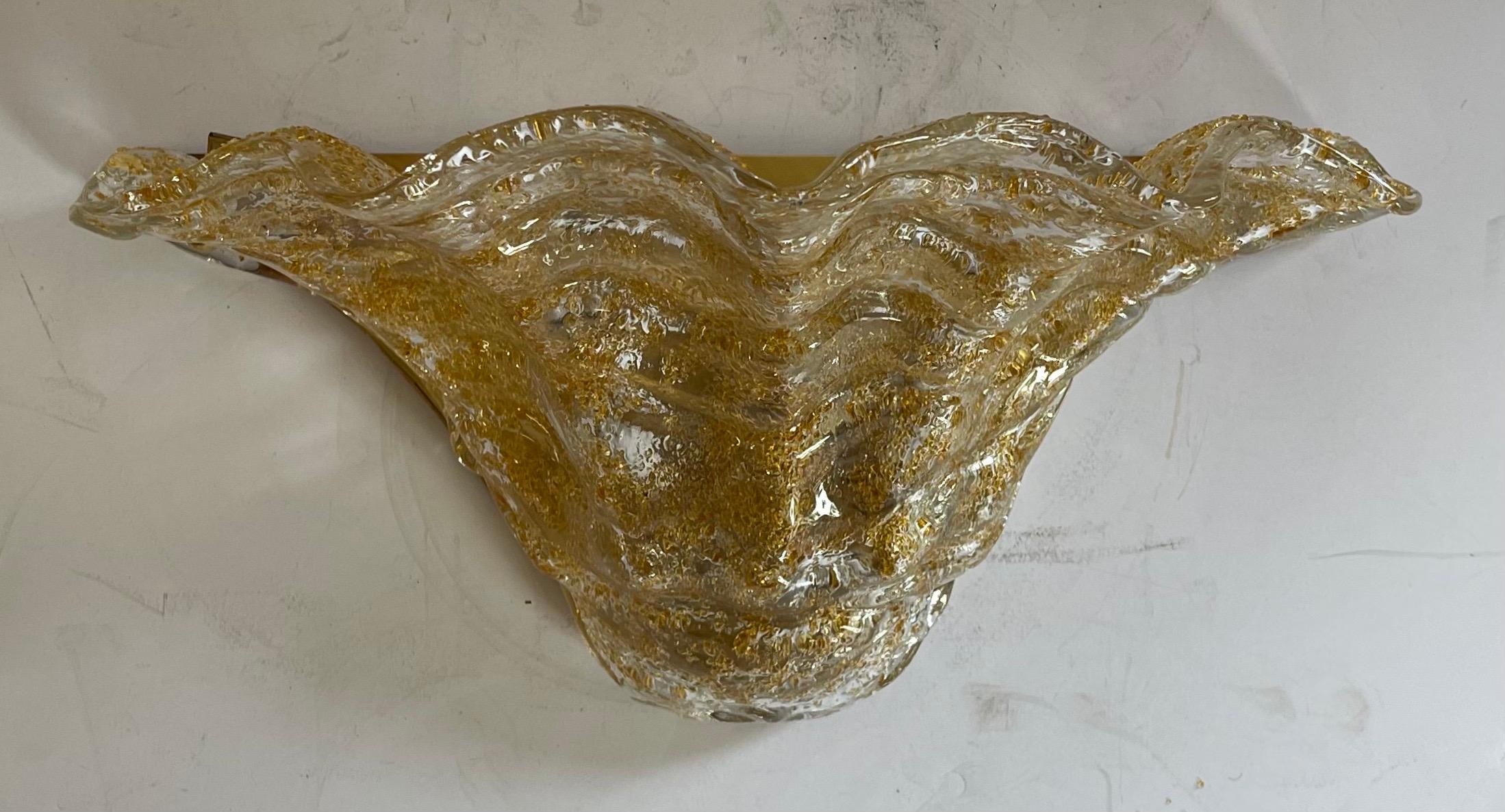 Eine wunderbare große Mid-Century Modern murano gold Kunstglas Satz von drei Wandleuchten mit Bronze Basis, montiert zusammen durch zwei Bronzekugeln.
Komplett neu verkabelt mit zwei Kandelaberfassungen zu je 40 Watt, inklusive aller Montageteile