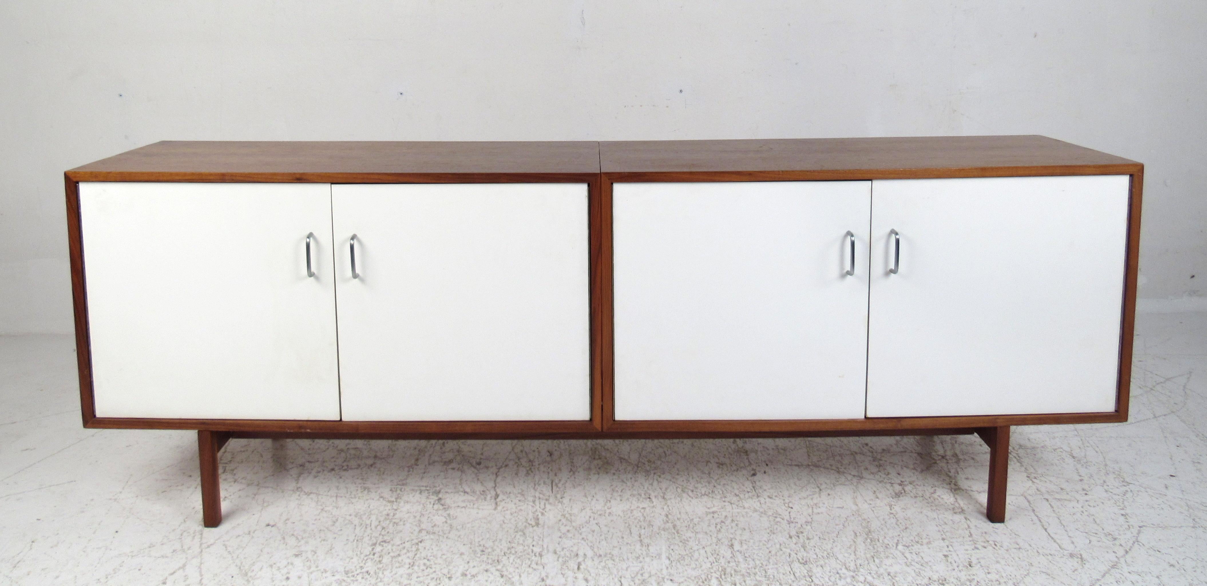 This stunning vintage modern sideboard features cabinet doors with white laminate fronts and metal handles. This three-piece unit boasts a walnut casing with gorgeous wood grain throughout. A large interior with dividers making this perfect for