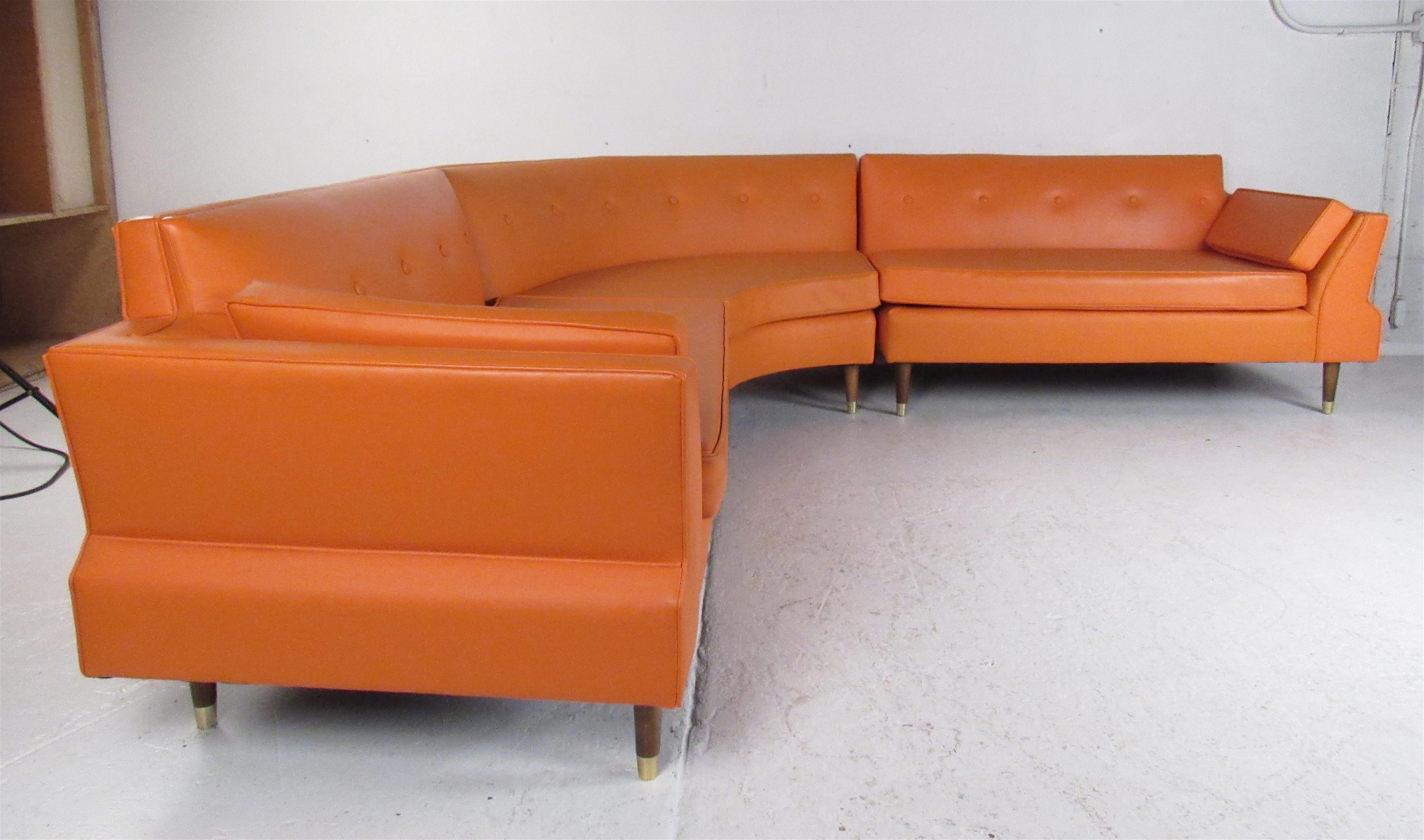 This amazing vintage modern three-piece sectional features an elaborate orange tufted vinyl upholstery. The overstuffed removable cushions, splayed armrests, and stubby walnut legs show quality. An extremely comfortable design with brass capped feet