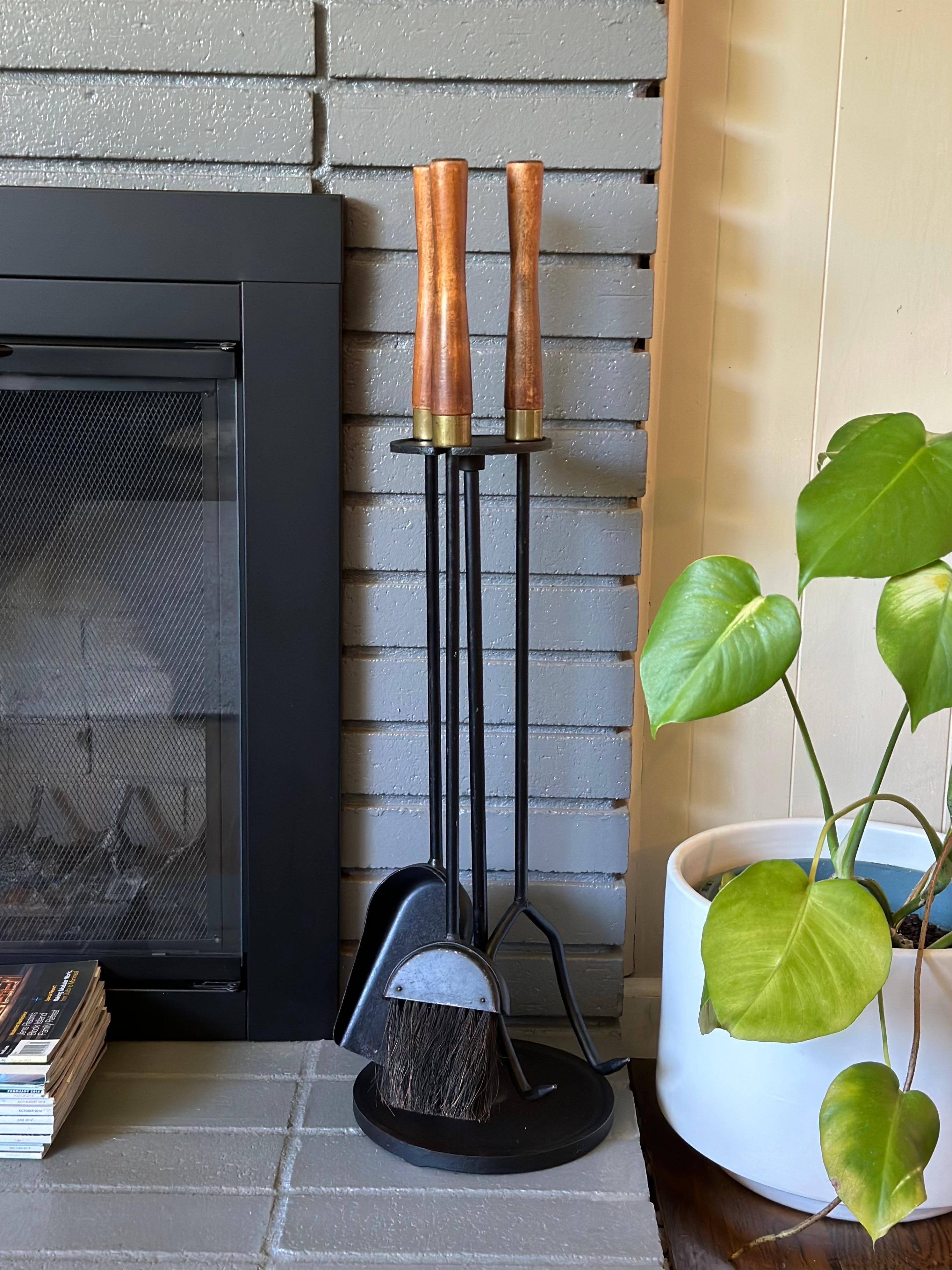 Vintage 3-piece fireplace tool set and floor stand circa 1960s. This set features sculpted wood handles with brass accents and a heavy cast iron base. Includes poker, shovel, brush, and floor stand.