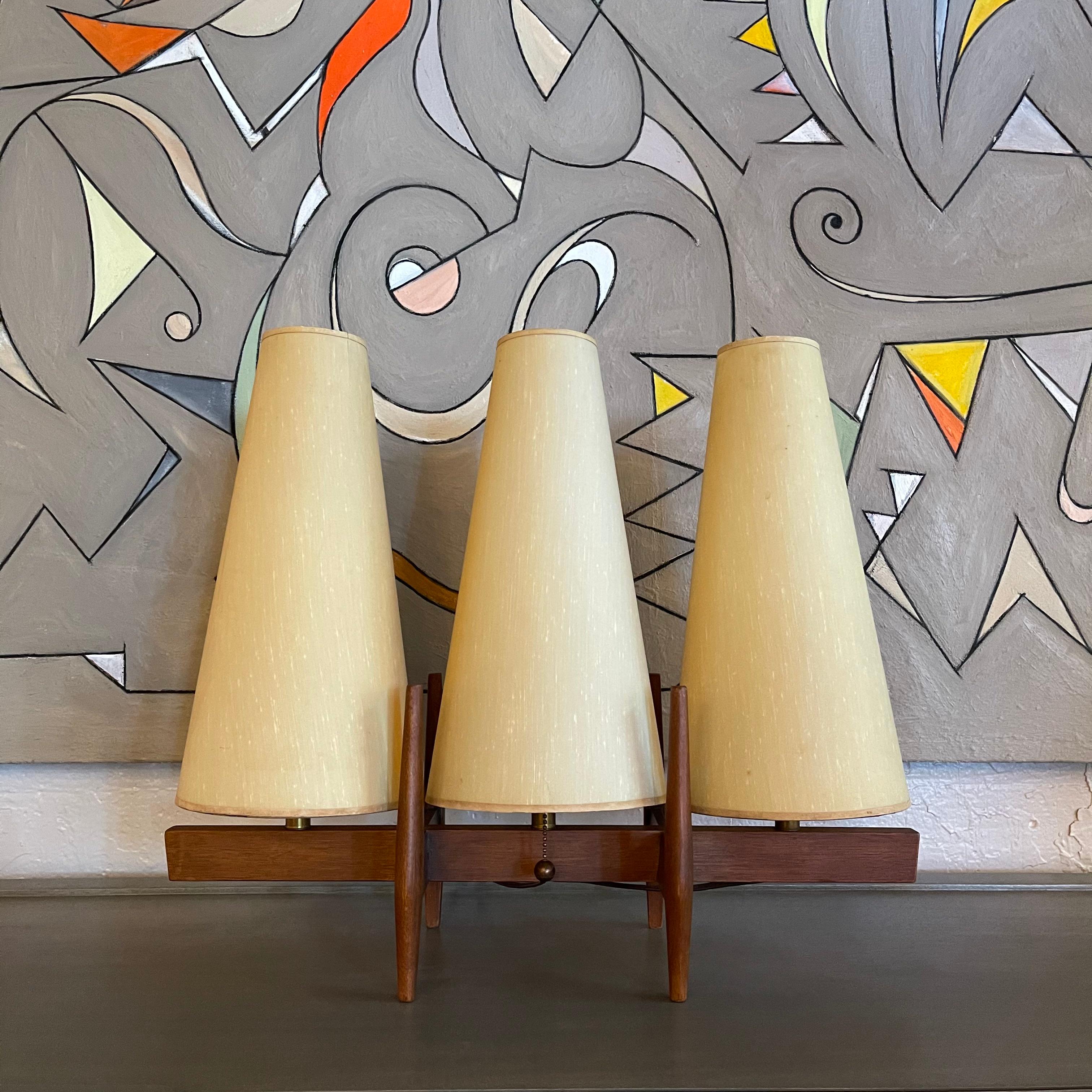 Fantastic, Mid-Century Modern, table lamp by Modeline attributed to John Keal features a walnut frame that accepts 3 bulbs covered with cone shaped, reinforced fabric shades in the texture of raw silk. The lamp has a pull chain that lights your
