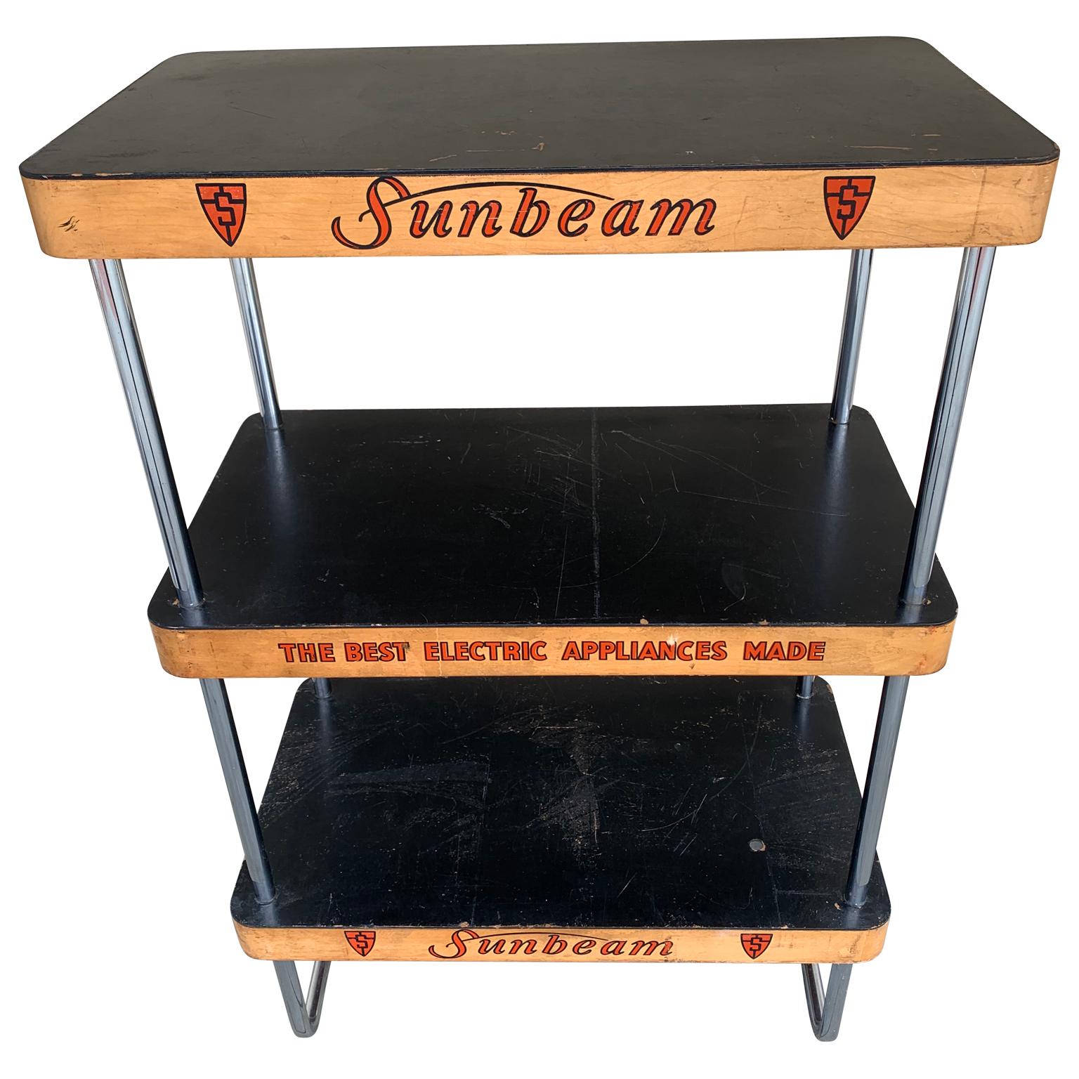 Mid-Century Modern Sunbeam appliance three-tier chrome and wood advertising shelving display case. Logo and company slogan is written in red letters on the sides of the shelves: 
