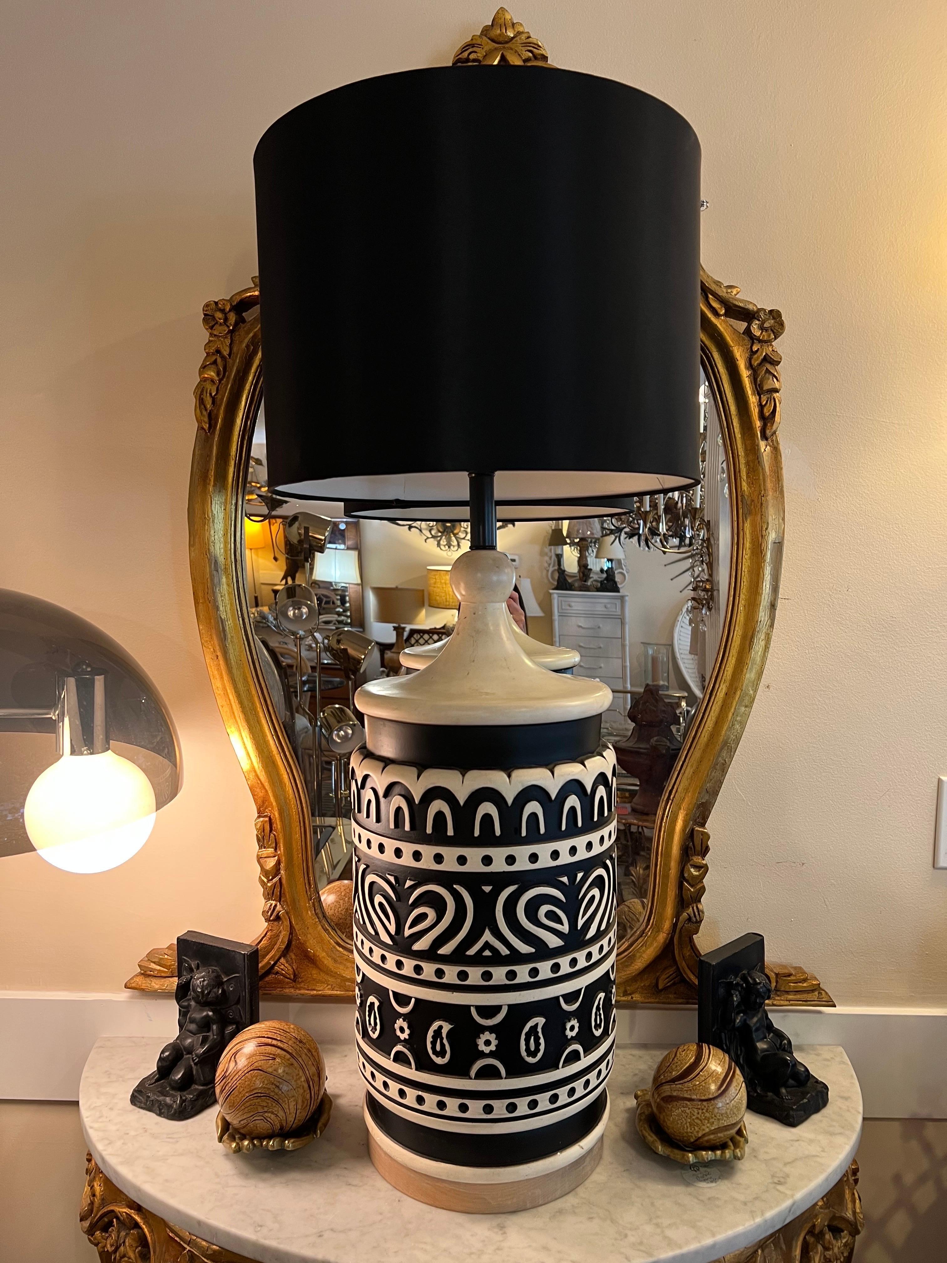 Lampe tiki en céramique du milieu du siècle. Lampe étonnante et unique en son genre avec des motifs géométriques et paisley détaillés en noir et crème. Elle possède une base en bois naturel en rond avec un abat-jour tambour en soie noire. La partie