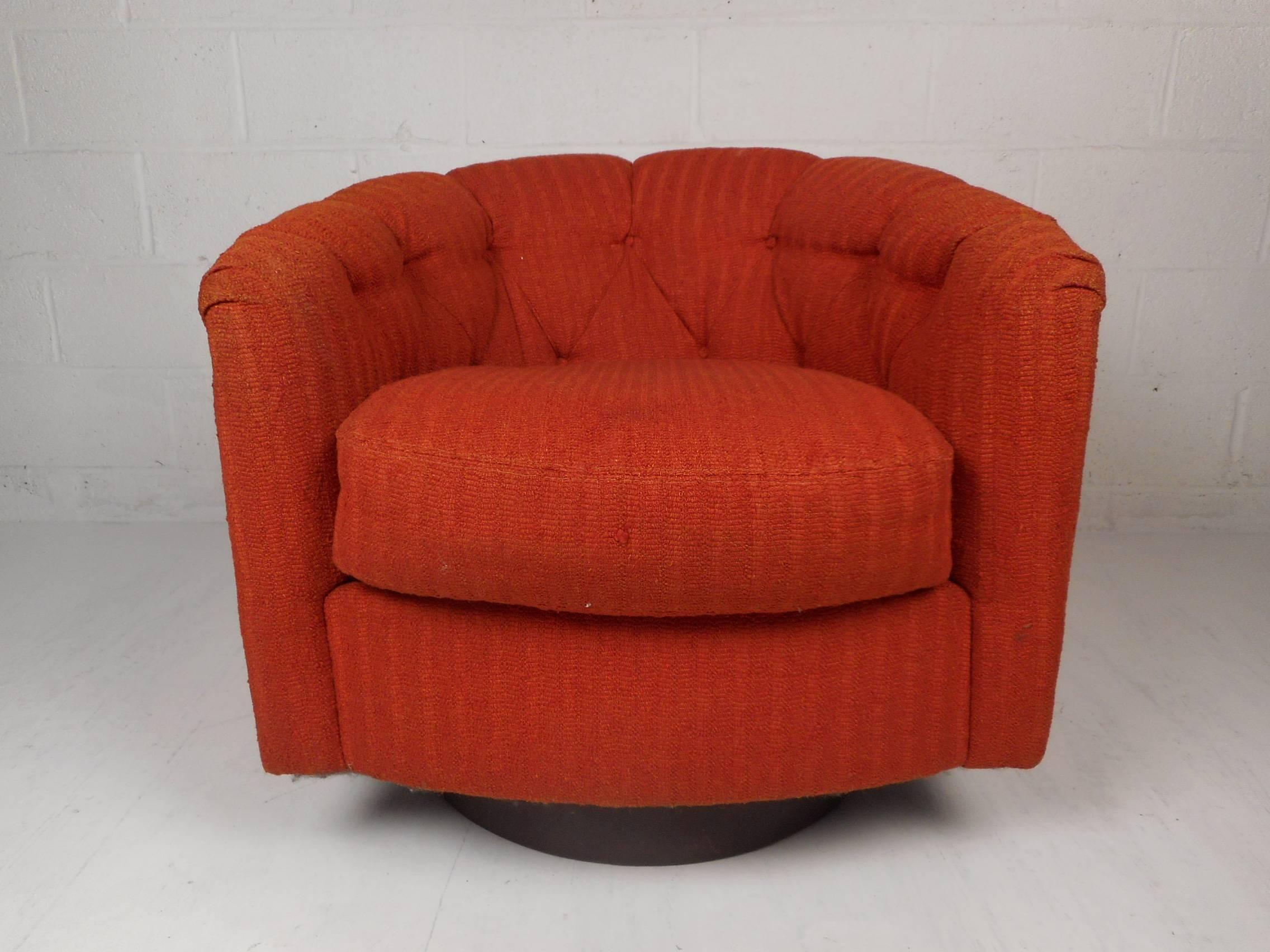 This beautiful vintage modern lounge chair has the ability to swivel and tilt with its versatile round walnut base. This wonderful chair is covered in plush orange upholstery and has an overstuffed removable cushion. Sleek design with a tufted