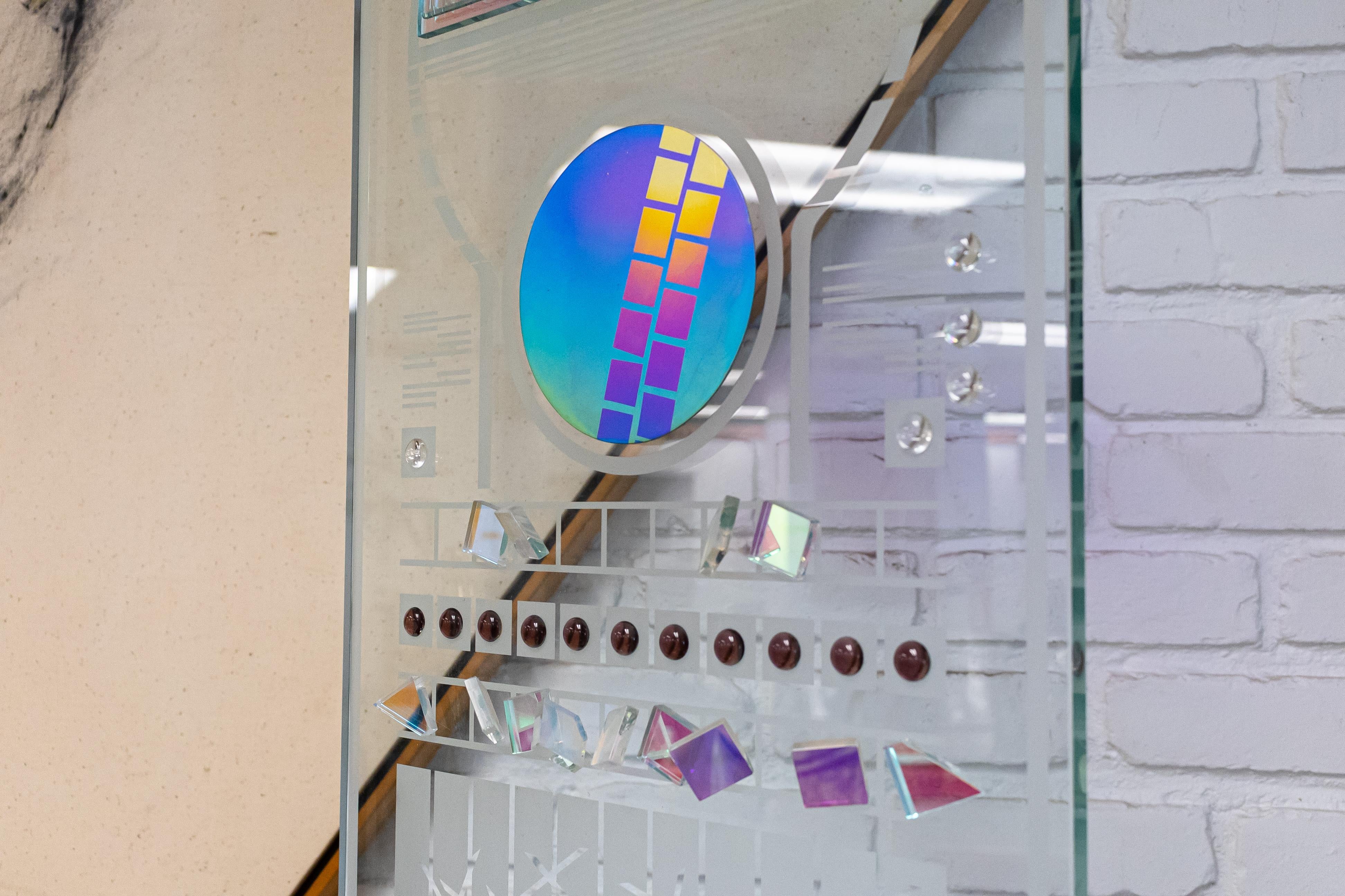 A very large glass sculpture by artist Toland Peter. This massive statement piece stands at 89.25 in tall, 16 in wide, and 13 in deep. It consists of a series of beautiful, eye catching designs on a tall glass panel. Pieces of the panel are colored,