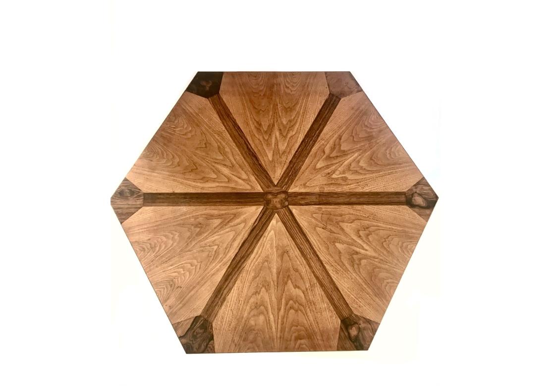 Mesa auxiliar o auxiliar hexagonal de la década de 1960, de Tomlinson Furniture, fabricada en madera de pacana con incrustaciones de caoba. La mesa tiene un tablero hexagonal coronado por patas facetadas curadas sobre una base