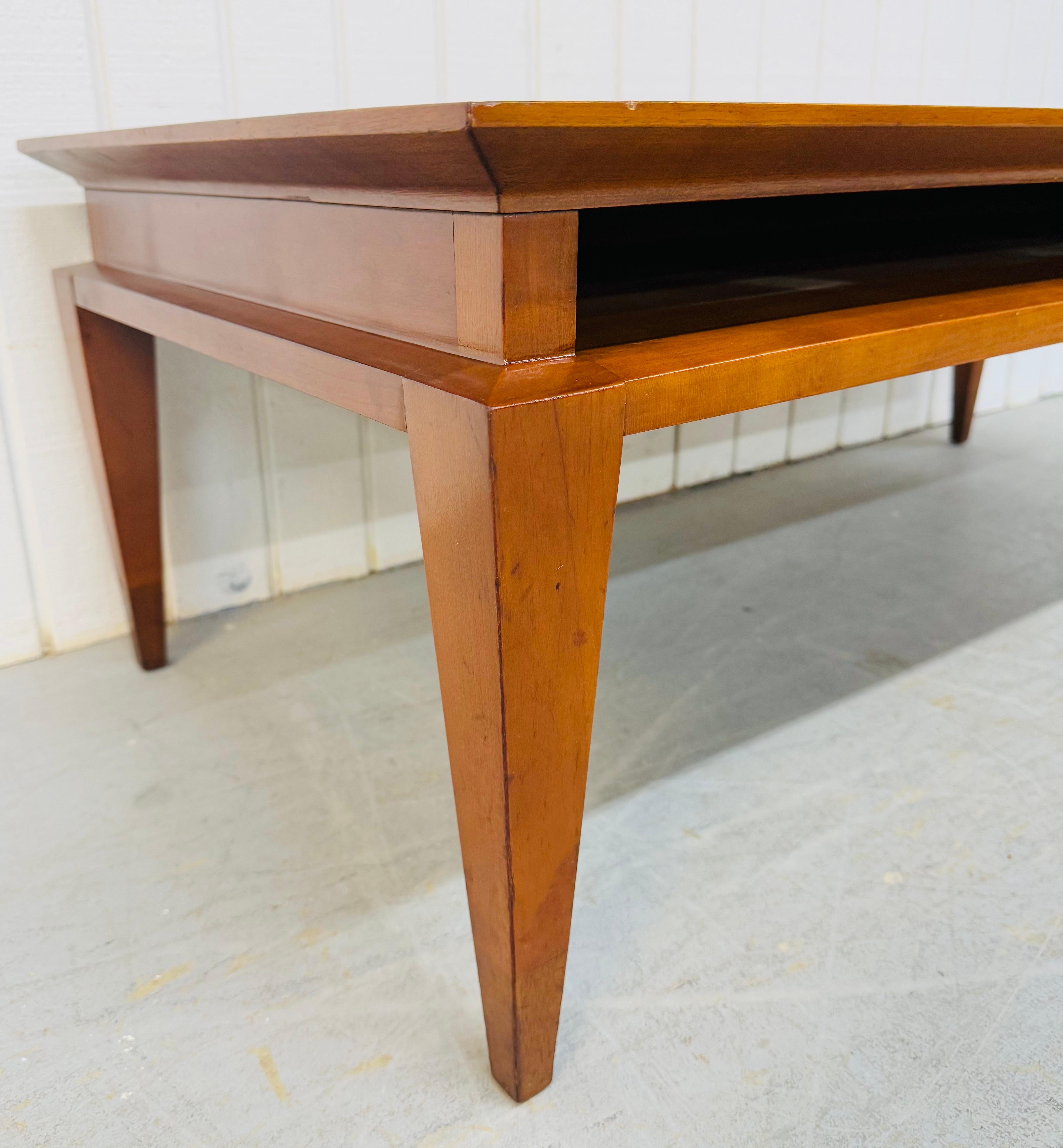 This listing is for a Mid-Century Modern Tomlinson Solid Cherry Wood Coffee Table. Featuring a straight line design, solid cherry wood construction, opening space for magazine storage, long modern legs, and a beautiful cherry finish. This is an