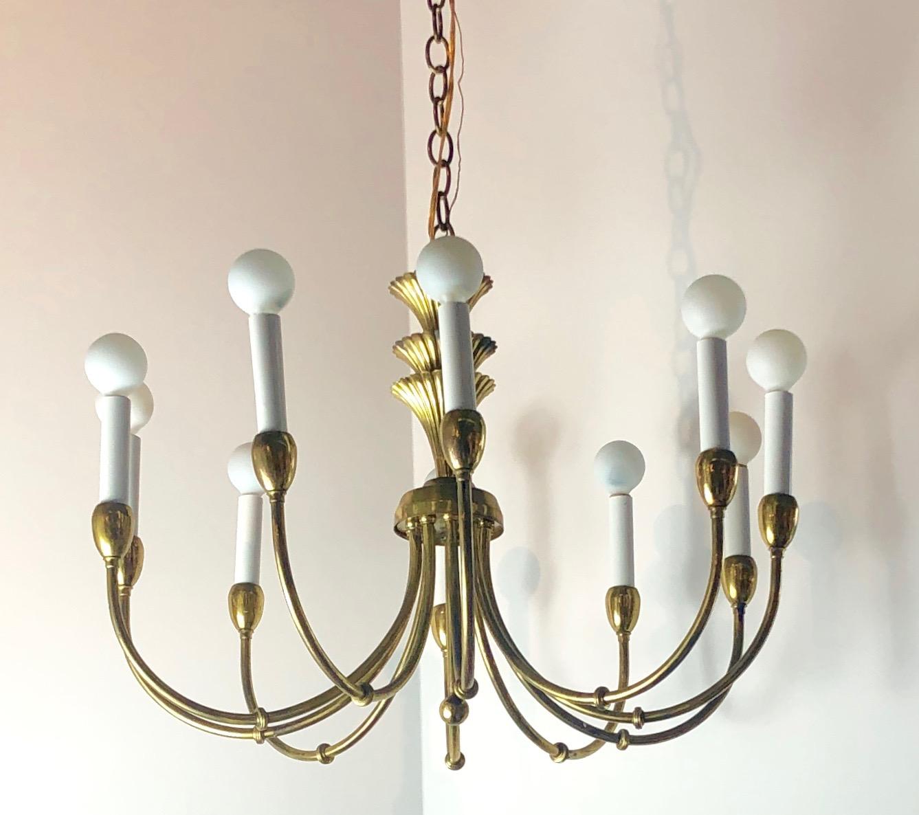 Offered is a Mid-Century Modern Tommi Parzinger style brass Art Deco or Hollywood Regency style chandelier with ten sculptural arms and ten torchères. The attention to elegant, yet clean and Classic design makes this chandelier so desirable some