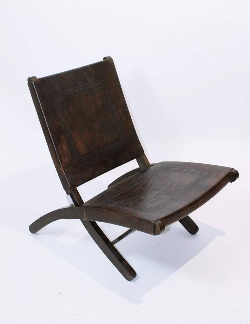 This Hungarian folding lounge chair is in the style of Hans J Wegner and was produced in the 1970s. The chair is made of brown hand-tooled cow leather.
