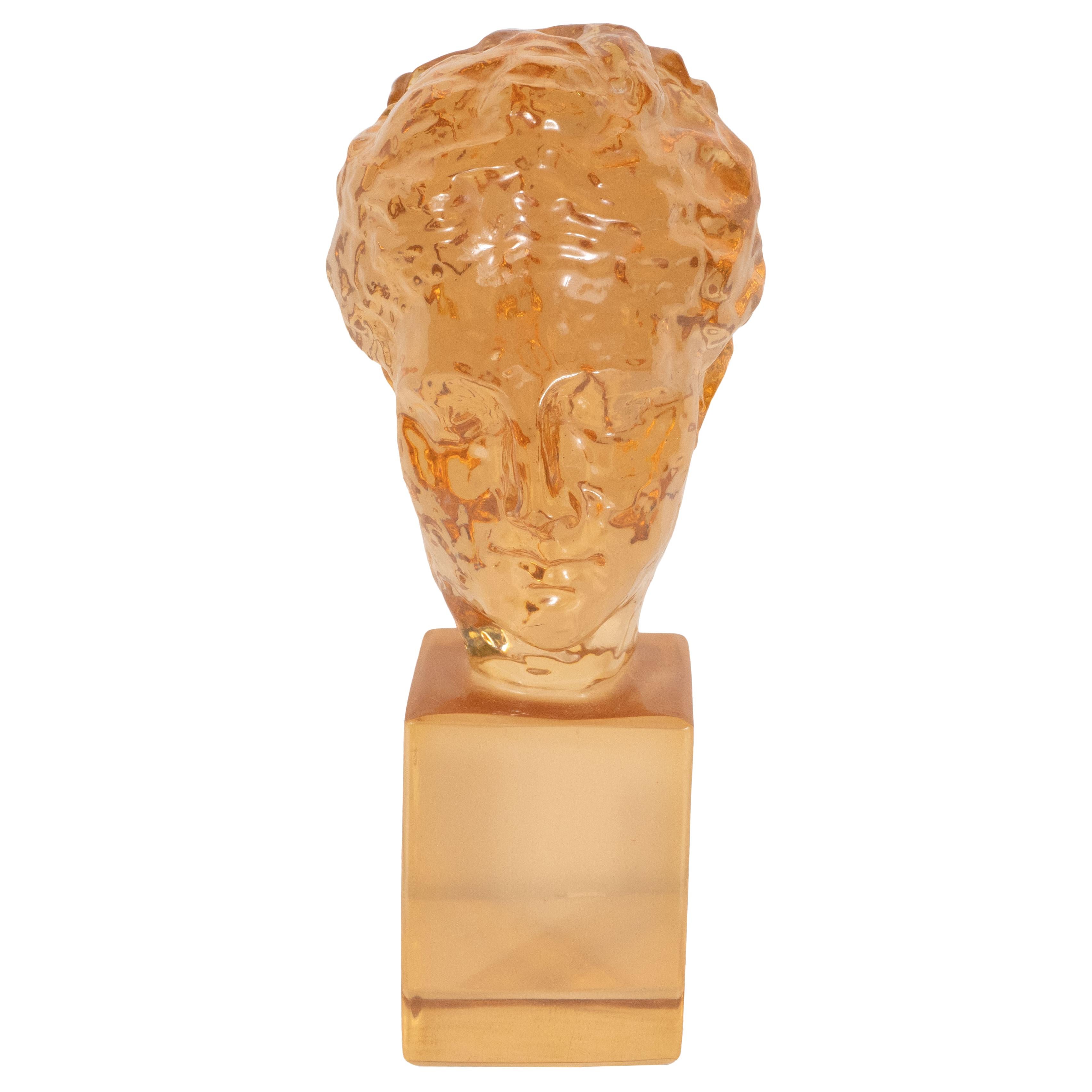 This sophisticated and dramatic sculpture was realized by the esteemed Mid-Century Modern designer- Dorothy Thorpe- in the United States, circa 1960. Created in translucent amber resin, the piece features a bust- suggesting a Classical Greek