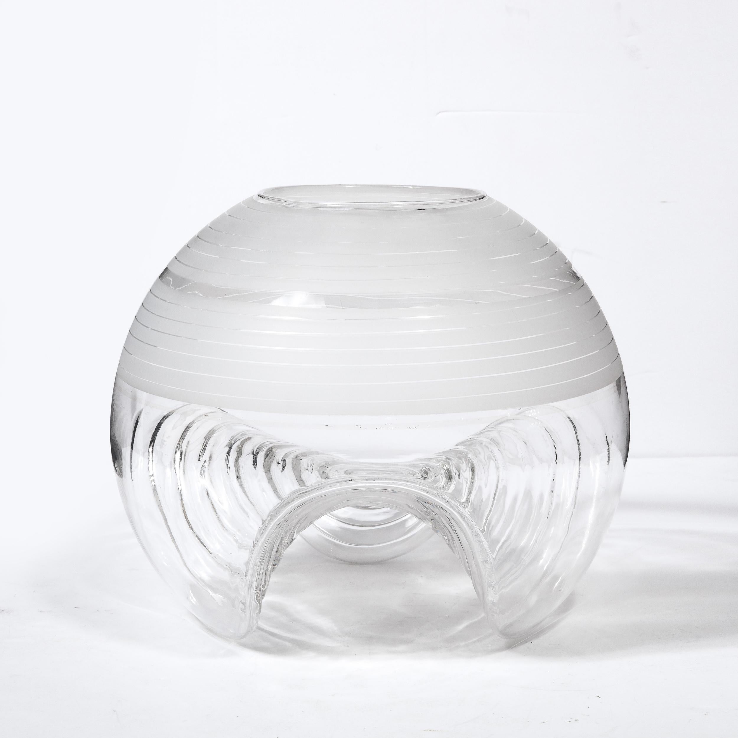 This refined Mid-Century Modern vase was realized by the esteemed maker Pell & Pulitzer in Germany circa 1970. It features a spherical body with sculptural undulating base in translucent glass with ribbon striations in relief incised into the