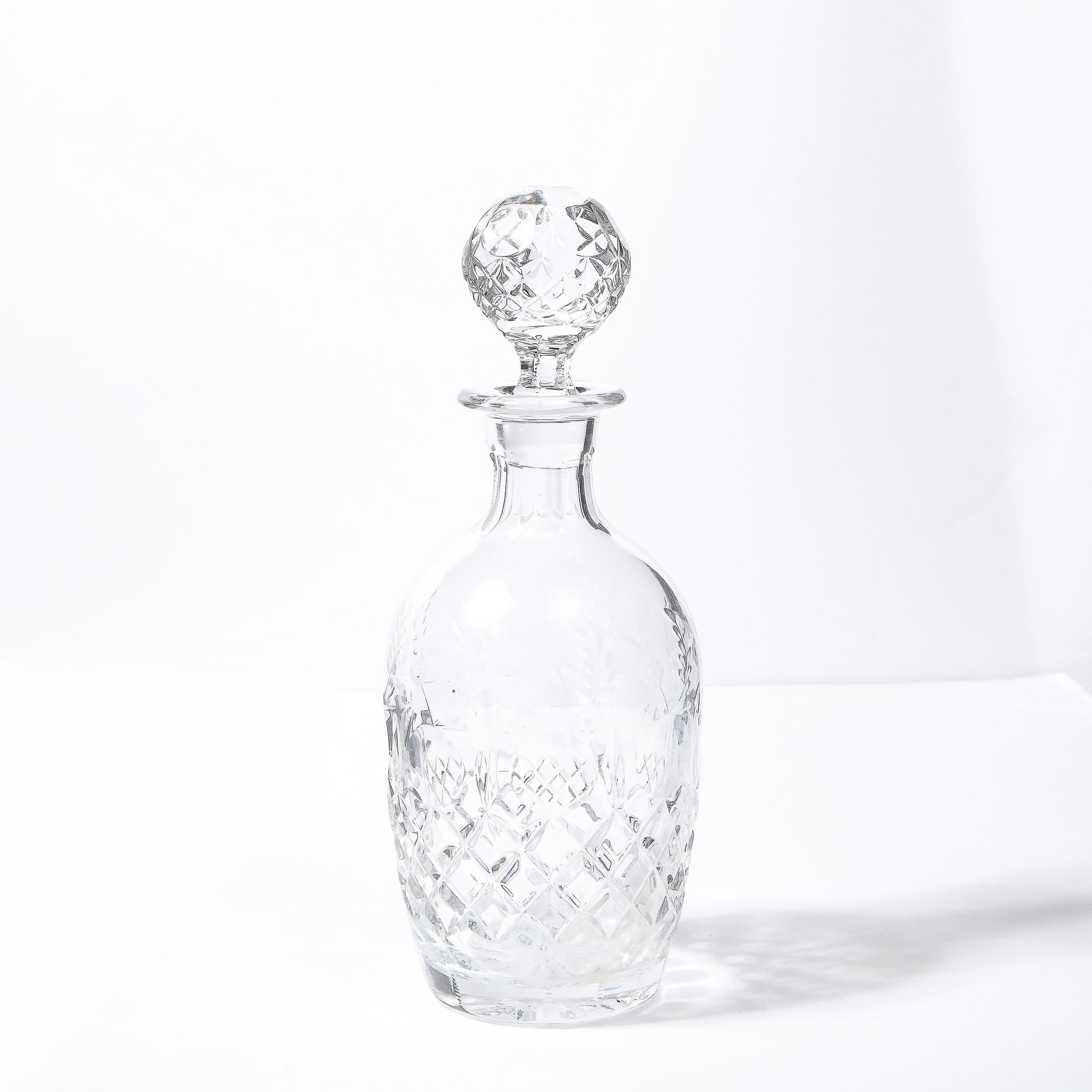 This elegant Mid-Century Modern crystal decanter was realized in the United States circa 1950. It features a cylindrical body with a finely proportioned neck that flares at its apex. A spherical etched crystal stopper with a cylindrical base neatly