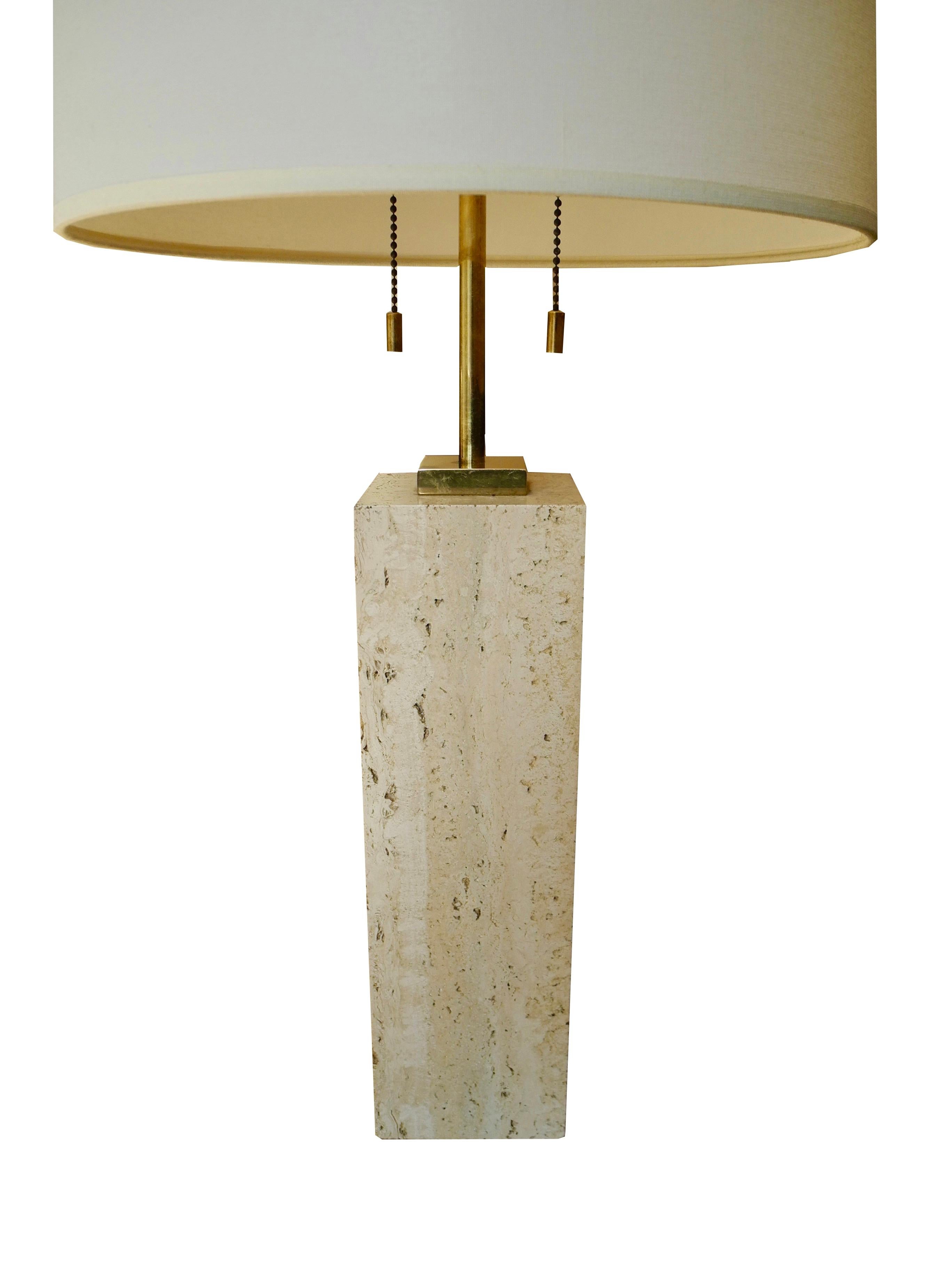This block of solid travertine stone and brass fittings was designed by TH Robsjohn-Gibbings in the 1950s. Its design is handsome and modern. The stone measures 4 x 4 x 13.5 inches. The height to the top of the finial is 27.25