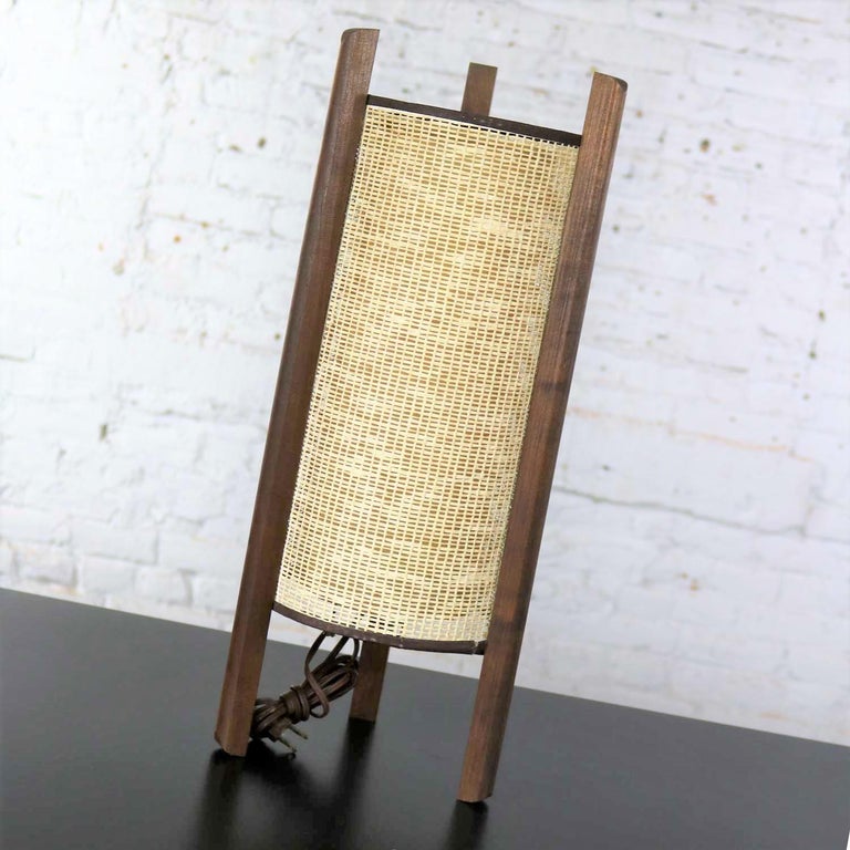 Handsome Mid-Century Modern tri-leg woven cylinder table lamp after the style of the famed Isamu Noguchi or the Danish modern styles of Modeline Lamp Company. It is comprised of a woven cylindrical shade with inner liner and walnut legs. This