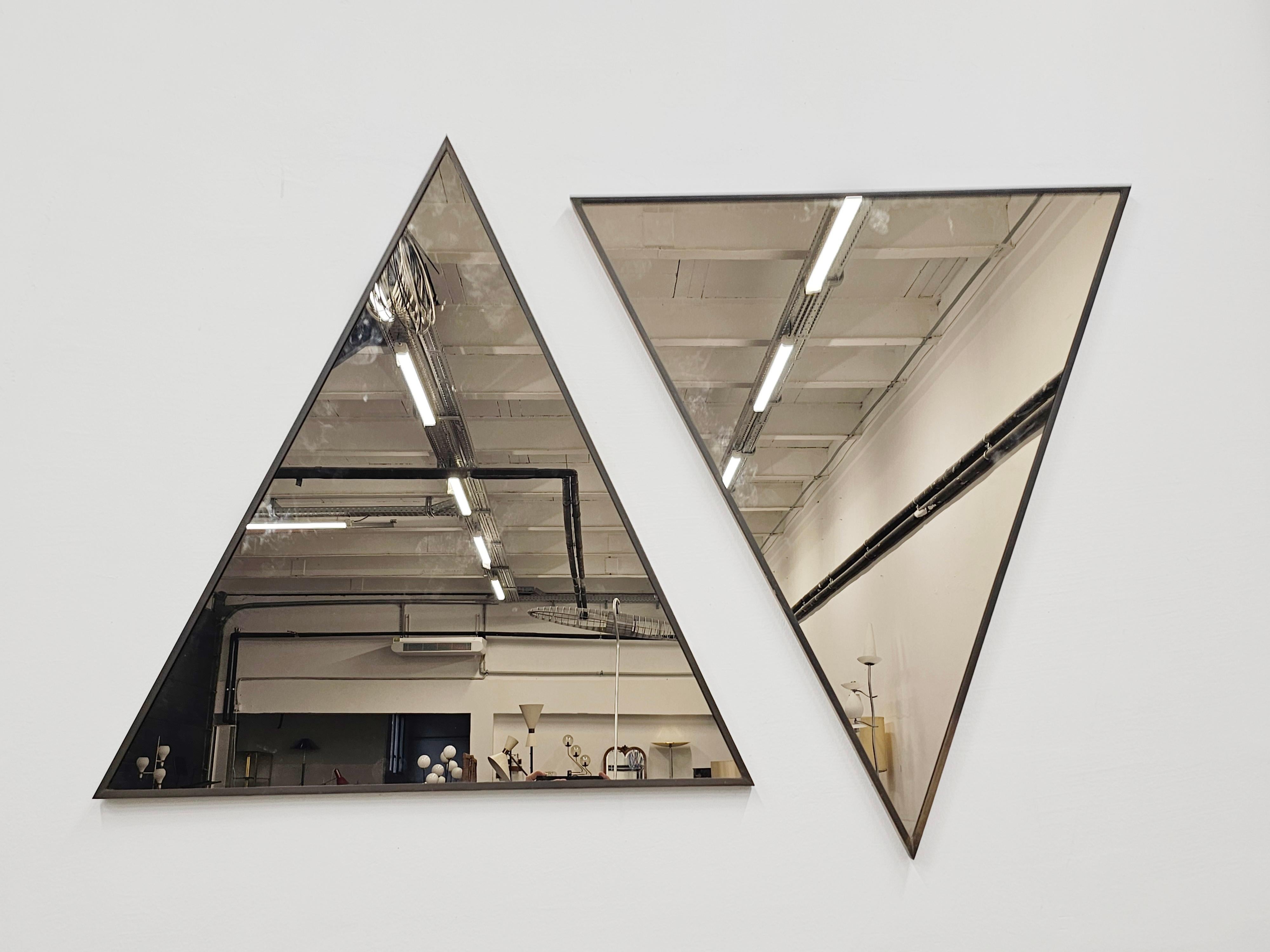 In this listing you will find a pair of exceptionally rare Mid Century Modern Triangular Mirrors. The mirror frames are done in bronze, while the mirror itself is tinted and has a color of bronze. The mirrors are made to be mounted at any corner of