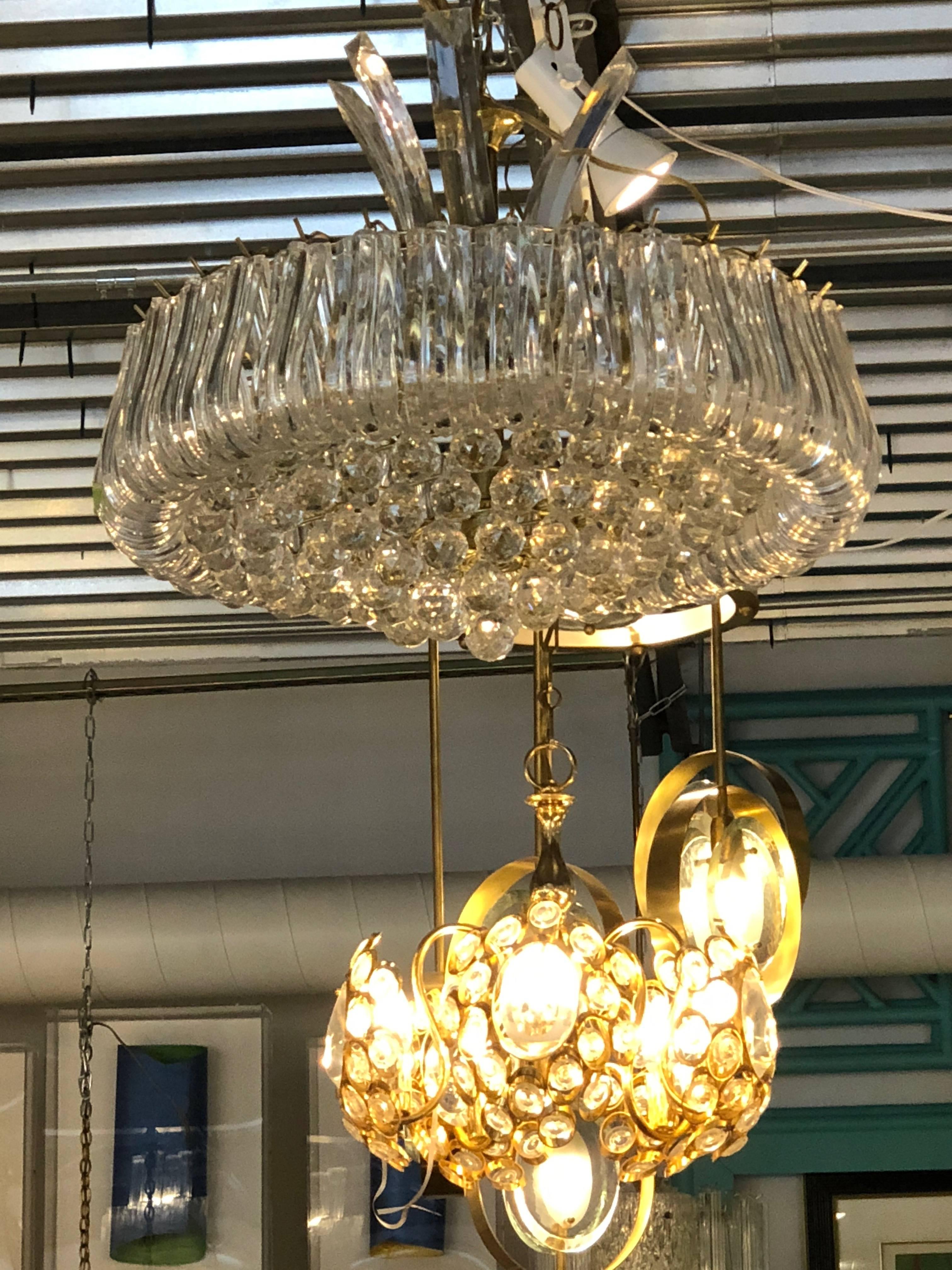 Offered is a mid century modern Triarch Lucite and brass chandelier.  Triarch International lighting is known for their amazing craftsmanship and high glamorous styles, shapes and finishes on each chandelier. Every product created by this company