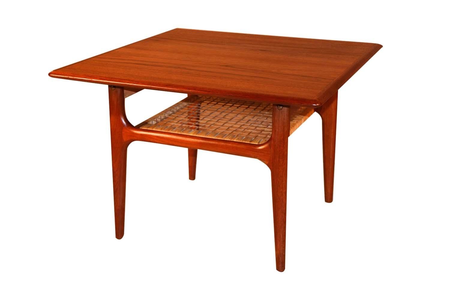 A beautifully crafted, Danish, two-tier, teak and cane table designed by Trioh Mobler, circa 1960s. This table features a sturdy two tier design with the bottom tier strongly supported by original woven cane. The second cane shelf adds additional