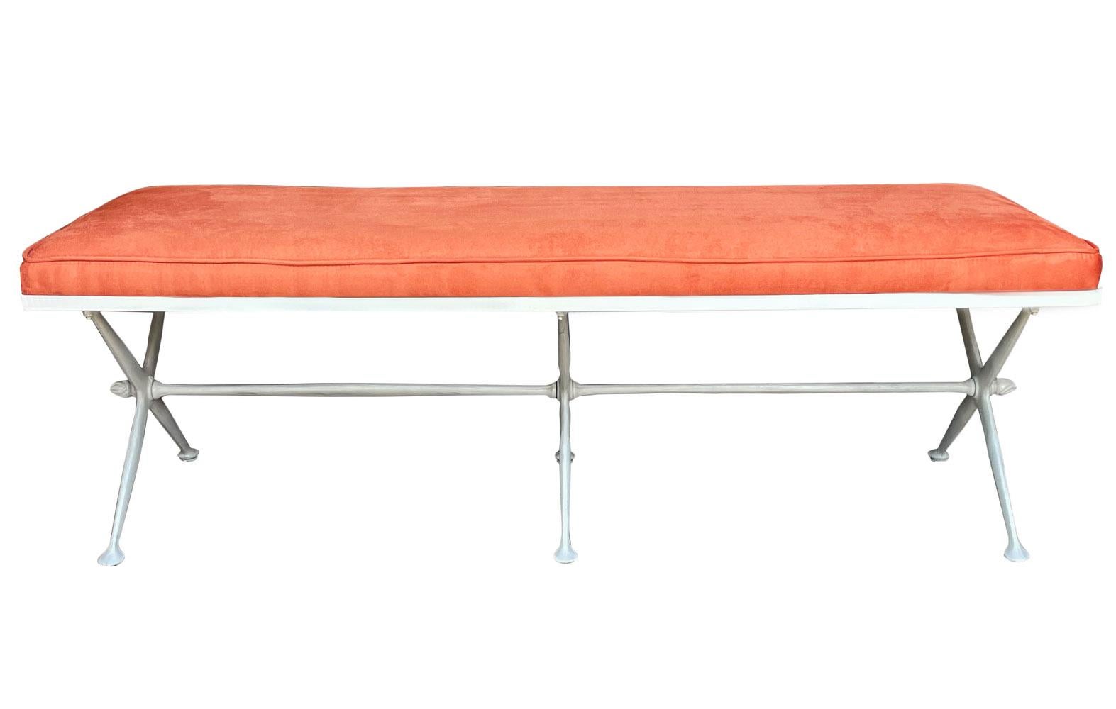A sleek modern bench circa 1960's. It features an off white powder coated cast aluminum X base with Orange velvet seat. Restored condition.