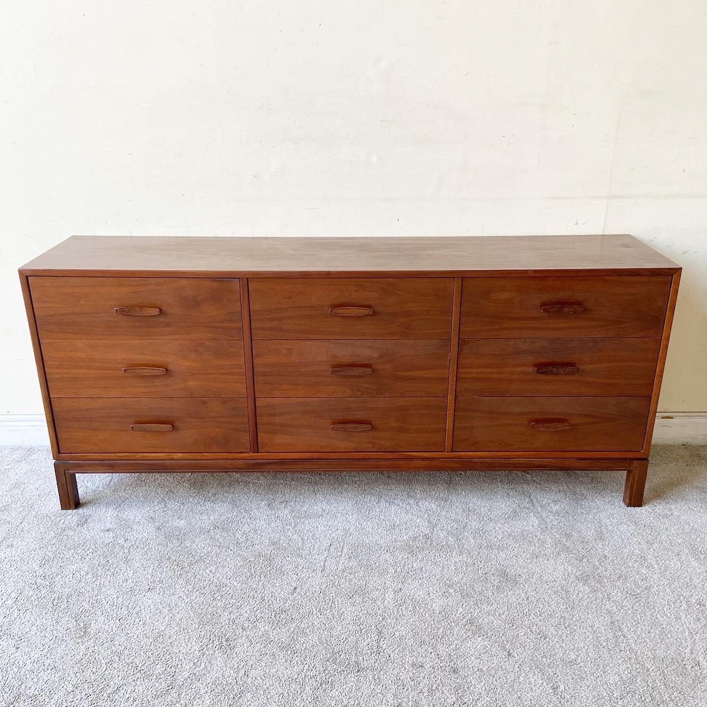 Phenomenal mid century modern wooden triple dresser. Features nine spacious drawer with carved drawer pulls.