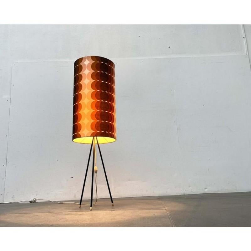 Lampadaire du milieu du siècle avec un motif d'abat-jour saisissant.
La lampe est dotée d'un simple trépied. Les tiges sont recouvertes de plastique noir et ont des capuchons blancs à la base. La particularité de la lampe est son abat-jour.