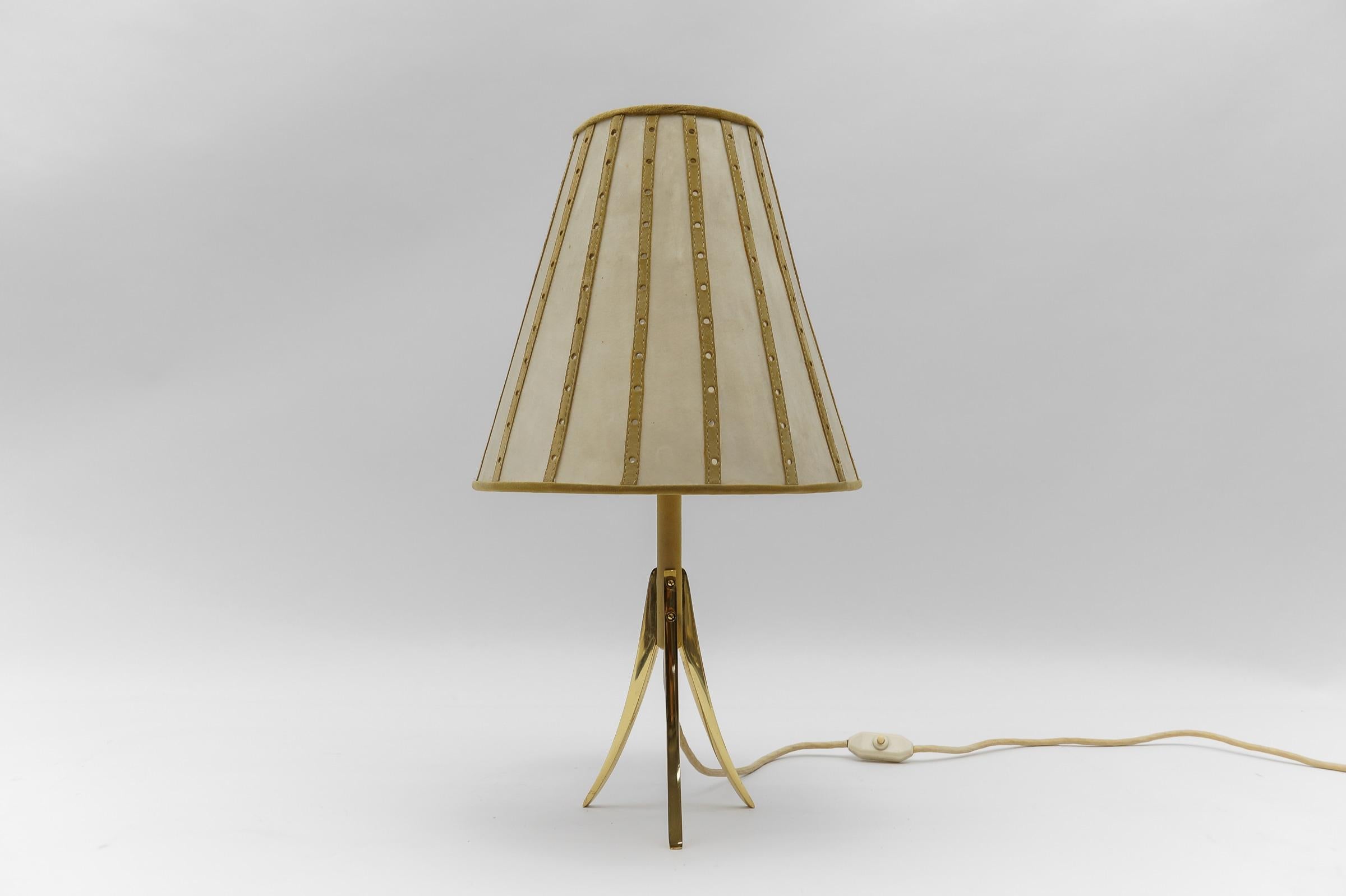Mid-Century Modern Tripod Table Lamp made in Brass and Leather, 1960s Austria

Dimension
Height: 21.65 in (55 cm)
Width: 11.82 in (30 cm)
Depth: 11.82 in (30 cm)

The lamp needs 1 x E27 / E26 Edison screw fit bulb, is wired, and in working