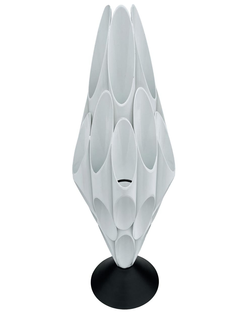 A sculptural table lamp made by Designline. It features all metal construction with bright white powder coated tubes and black base. It takes one standard bulb up to 100 watts. It has a very long cord with the on / off switch.