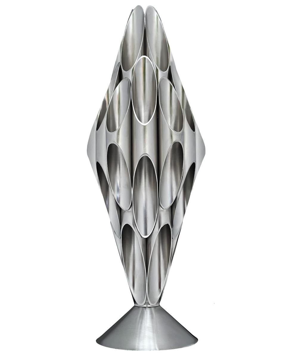 A sculptural table lamp made by Designline. It features heavy chrome construction with sliced nickel tubes. It takes one standard bulb up to 100 watts. It has a very long cord with the on / off switch.