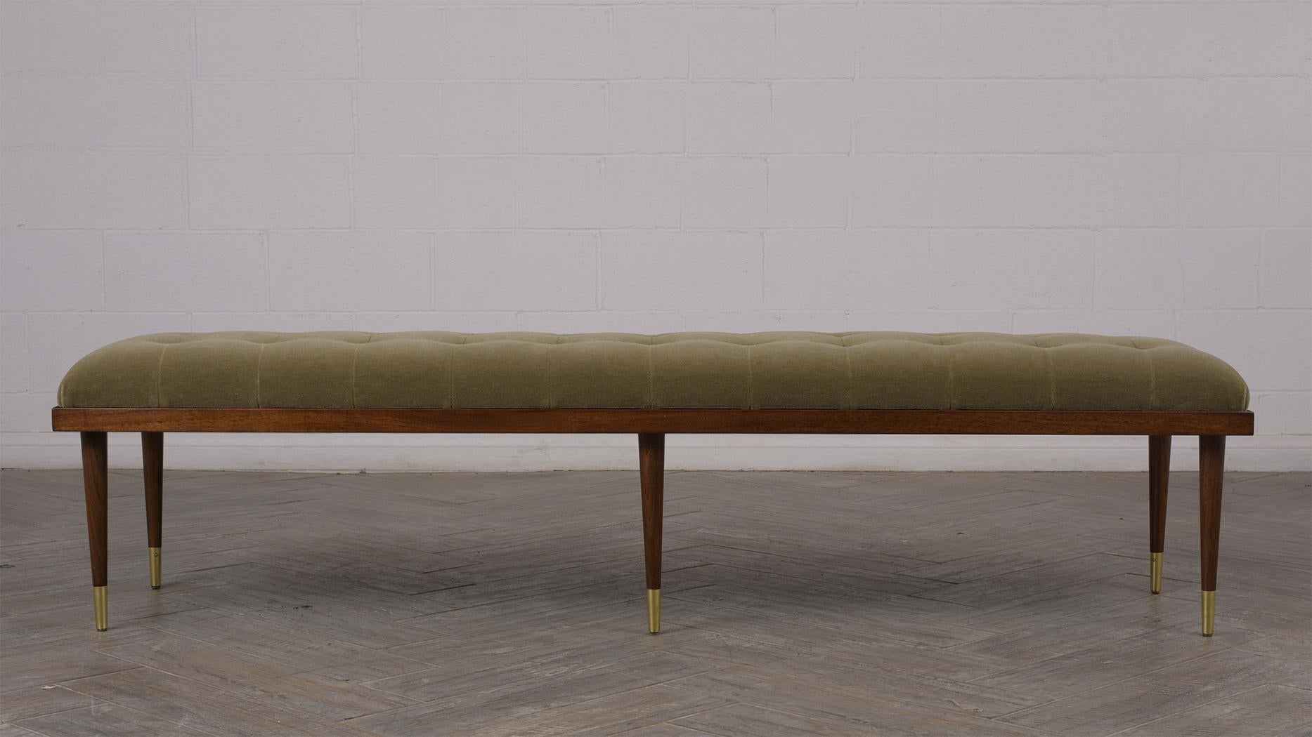 This Mid-Century Modern Bench features professionally upholstered in a green Mohair fabric with a tufted square design and top stitch detail. The bench rests on six solid teak wood legs stained in stunning dark walnut color and has polished brass