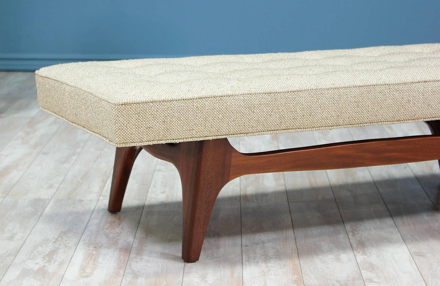 Mid Century Modern Bench manufactured in the United States circa 1960’s. This elegant bench features a sculptural solid walnut base and a new foam cushion upholstered with tufting in a textured cream-colored tweed fabric.