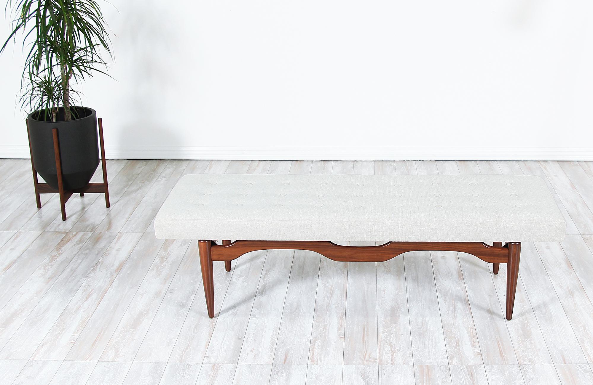Mid-Century Modern bench designed and manufactured in the United States circa 1960s. A comfortable modern bench featuring a sculptural solid walnut wood base and new tweed upholstery with an elegant tufted detail making an excellent option for