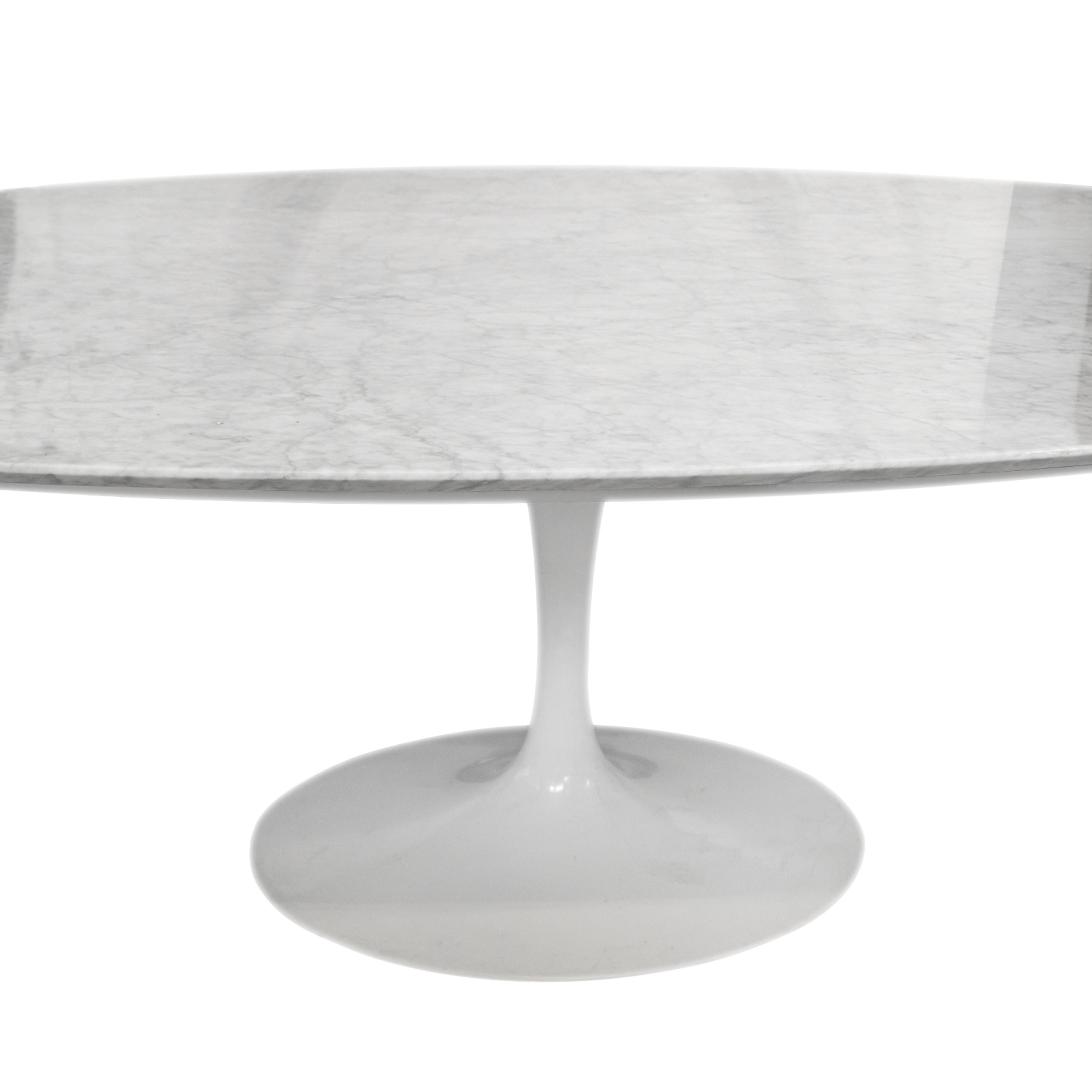 Tulip-style dining table, designed by Eero Saarinen, made of a white lacquered metal base, and an oval carrara marble tabletop.