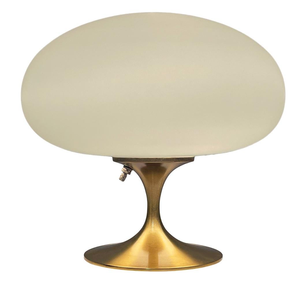 A gorgeous tulip form table lamp after Laurel Lamp company. It features a brushed brass cast aluminum base with mouth blown frosted white glass shades. It takes one standard bulb up to 100 watts.