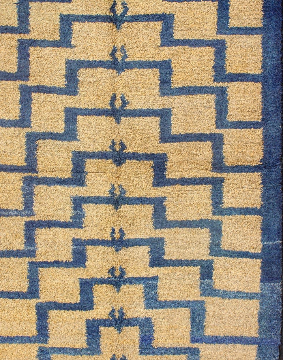 This vintage Tulu from mid-20th century Turkey boasts a mid century modern design with interconnected tribal pattern. The multi-tiered pattern consists of soft gold outlines set on a blue field. The contrast of color adds a particular depth to