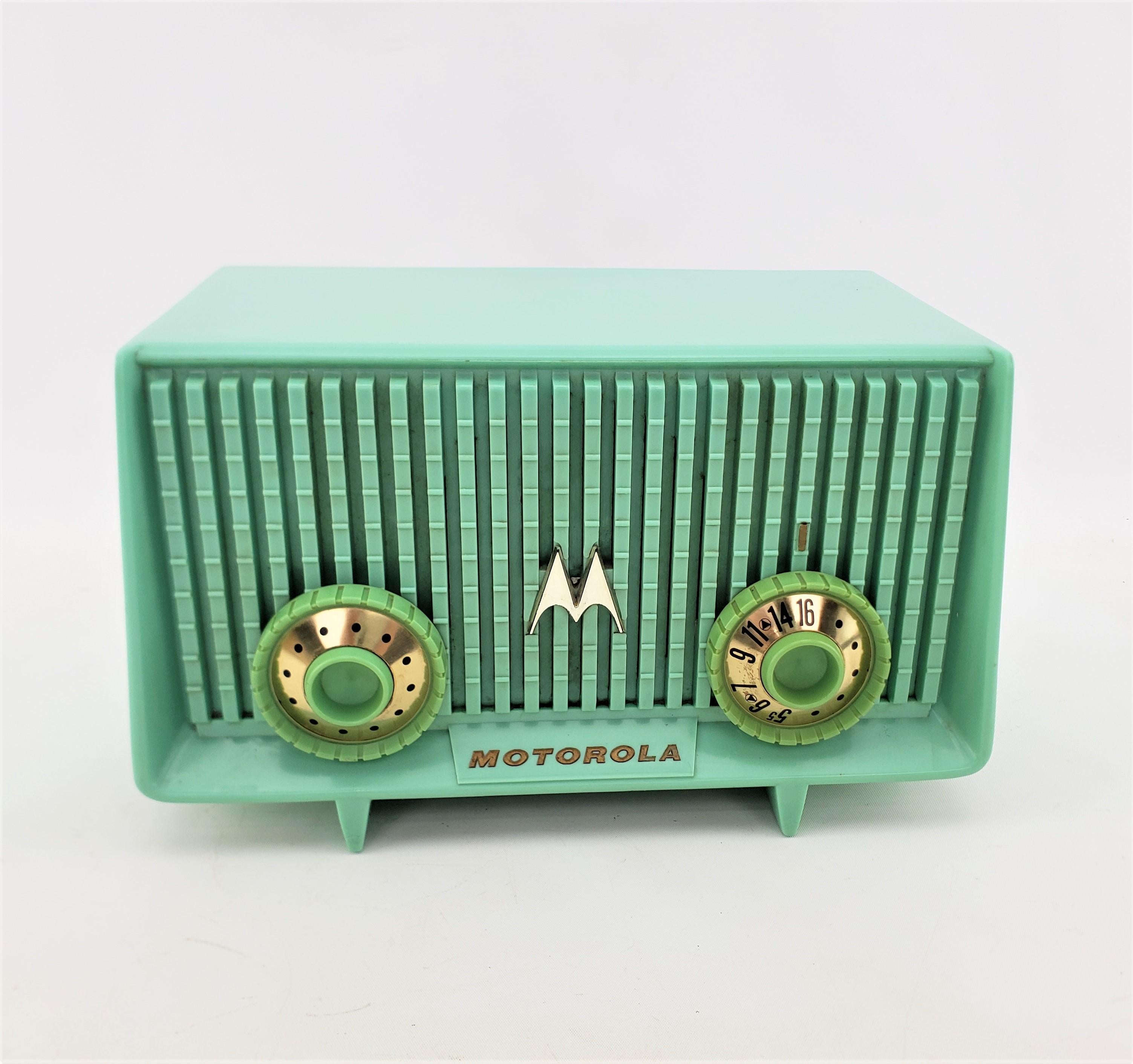 This vintage table radio was made by the Motorola company in a Canadian division, in approximately 1960 in the period Mid-Century Modern style. The case of the radio is a molded turquoise plastic with molded jadeite colored knobs with gold accents.
