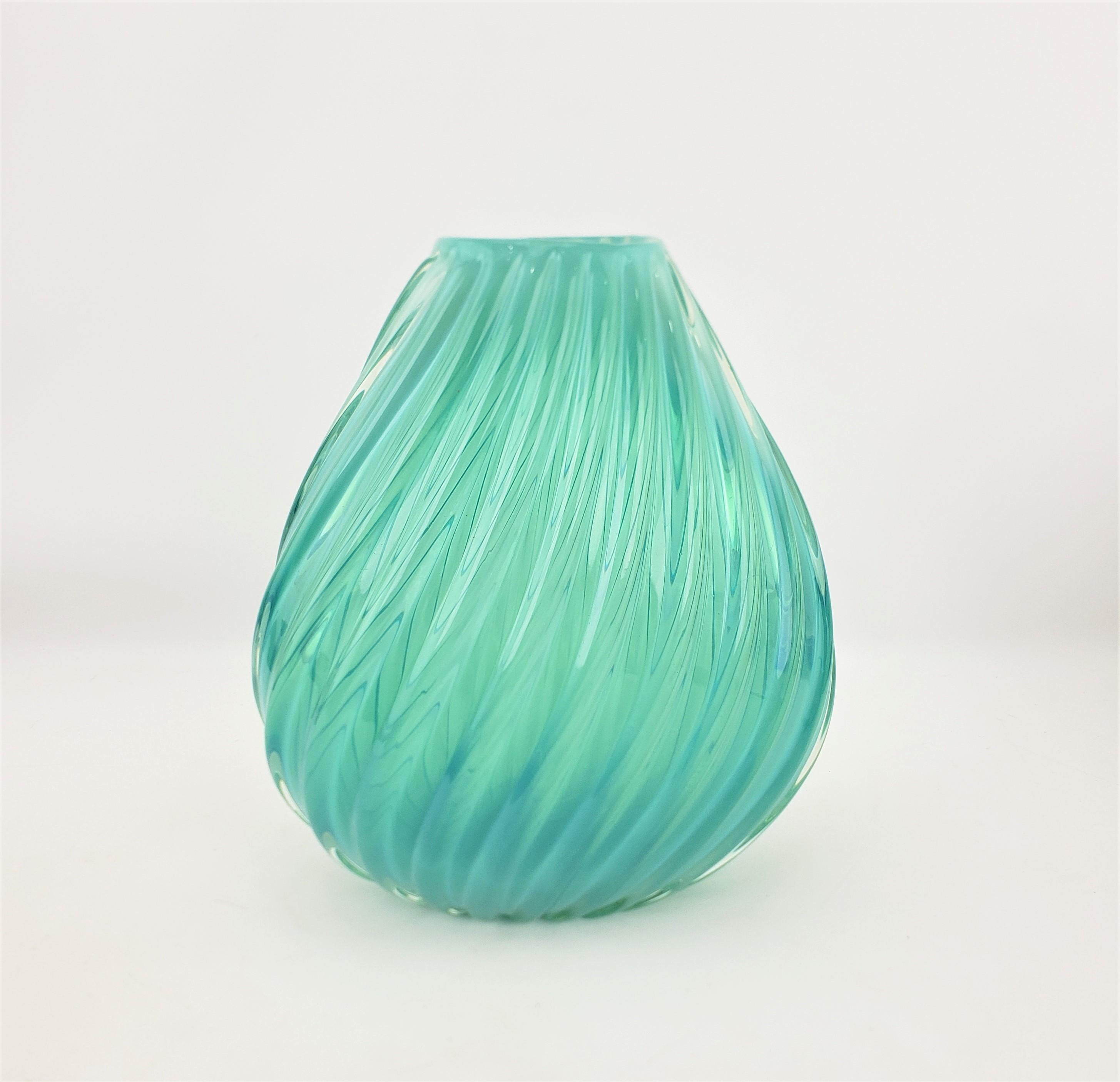 This Mid-Century art glass vase is unsigned, but presumed to have originated from Italy and dating to approximately 1965. This gourd shaped vase is done in a thick aquamarine glass with a swirled ribbing that runs from the top, down to the base.