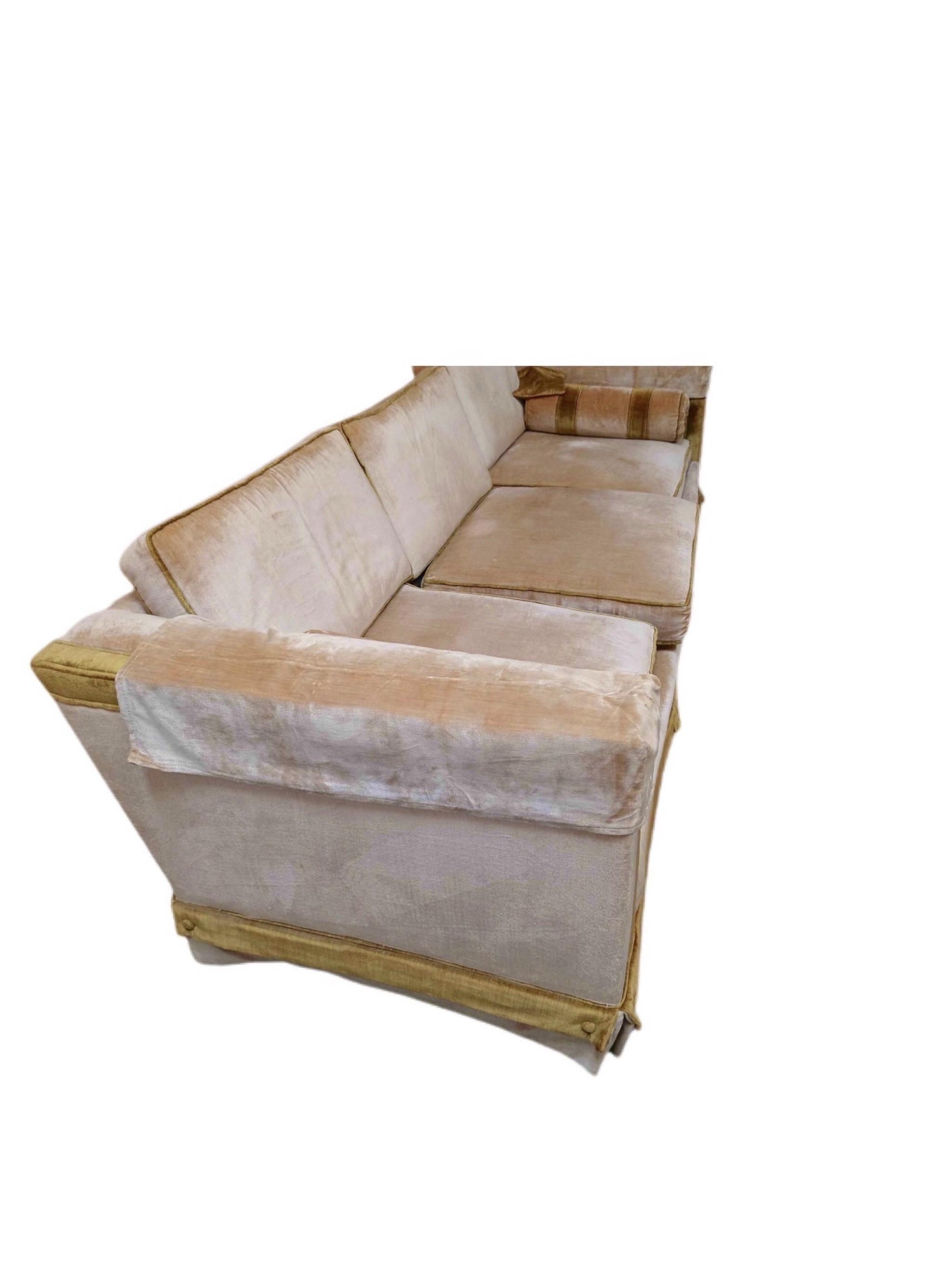 This exceptional piece of furniture is tuxedo style, with custom upholstery. It is upholstered in a pale peach with a green trim. This 3 cushion sofa can easily translate to fit into most decorating styles. It can be glamorous and chic or funky