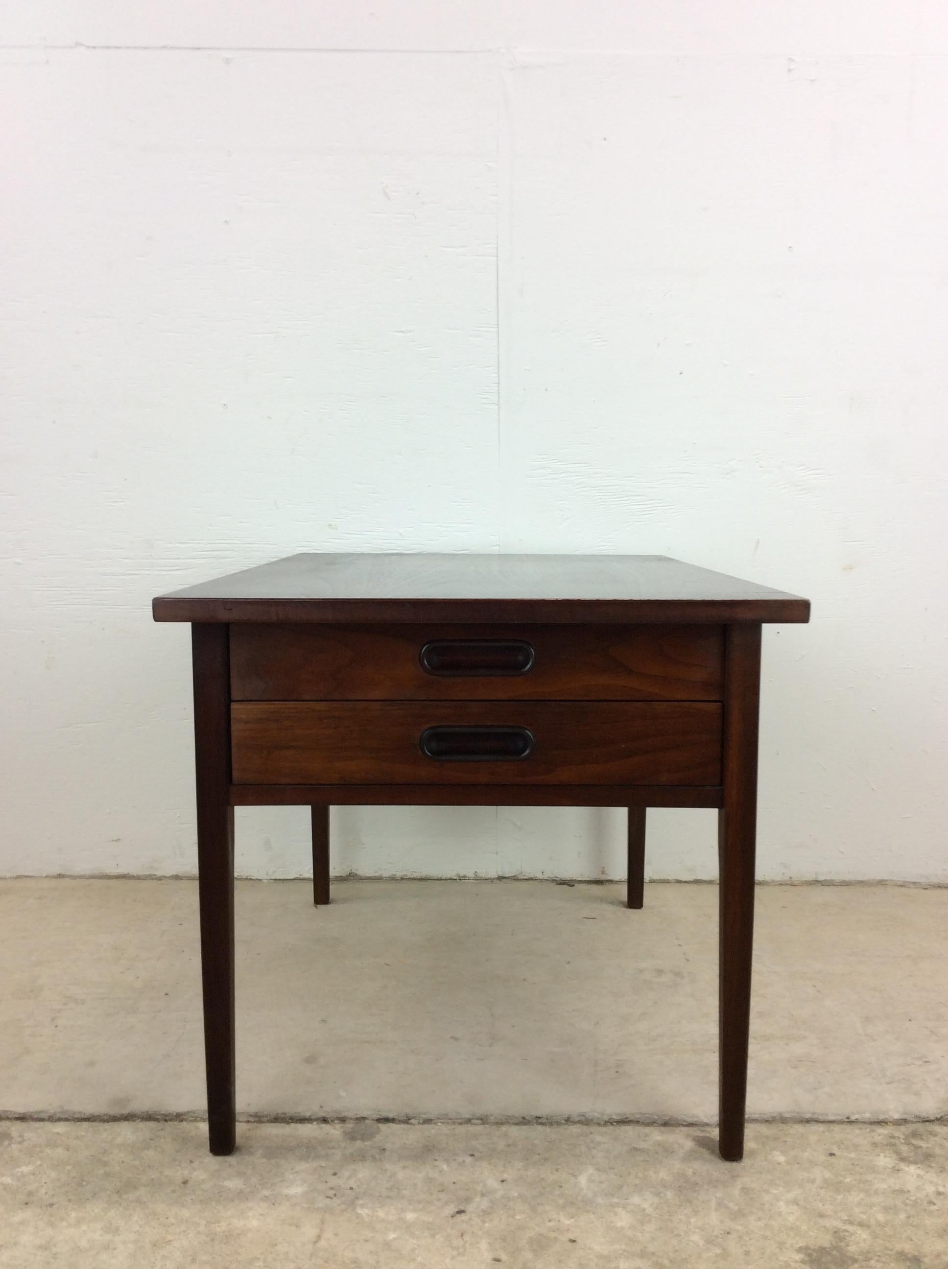 This mid century modern two drawer end table features hardwood construction, original dark walnut finish, two dovetailed drawers with carved wood pulls, and tall tapered legs. 
Dimensions: 21w 130d 35h 21.25sh

Condition: Original dark finish has