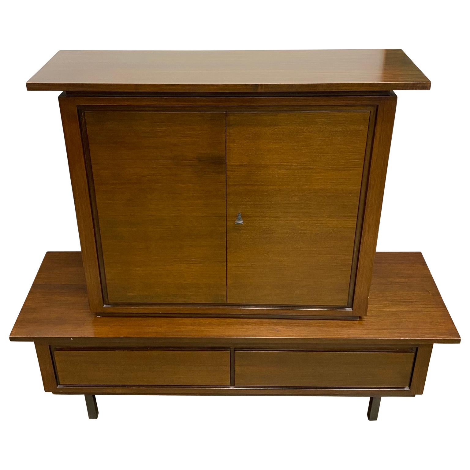 Mid-Century Modern dry bar and credenza set. This unusual, understated piece is in original condition with a glowing walnut finish, having a heavy triangular iron key, Birdseye maple interior, mirrored back and elegant black glass top shelf with