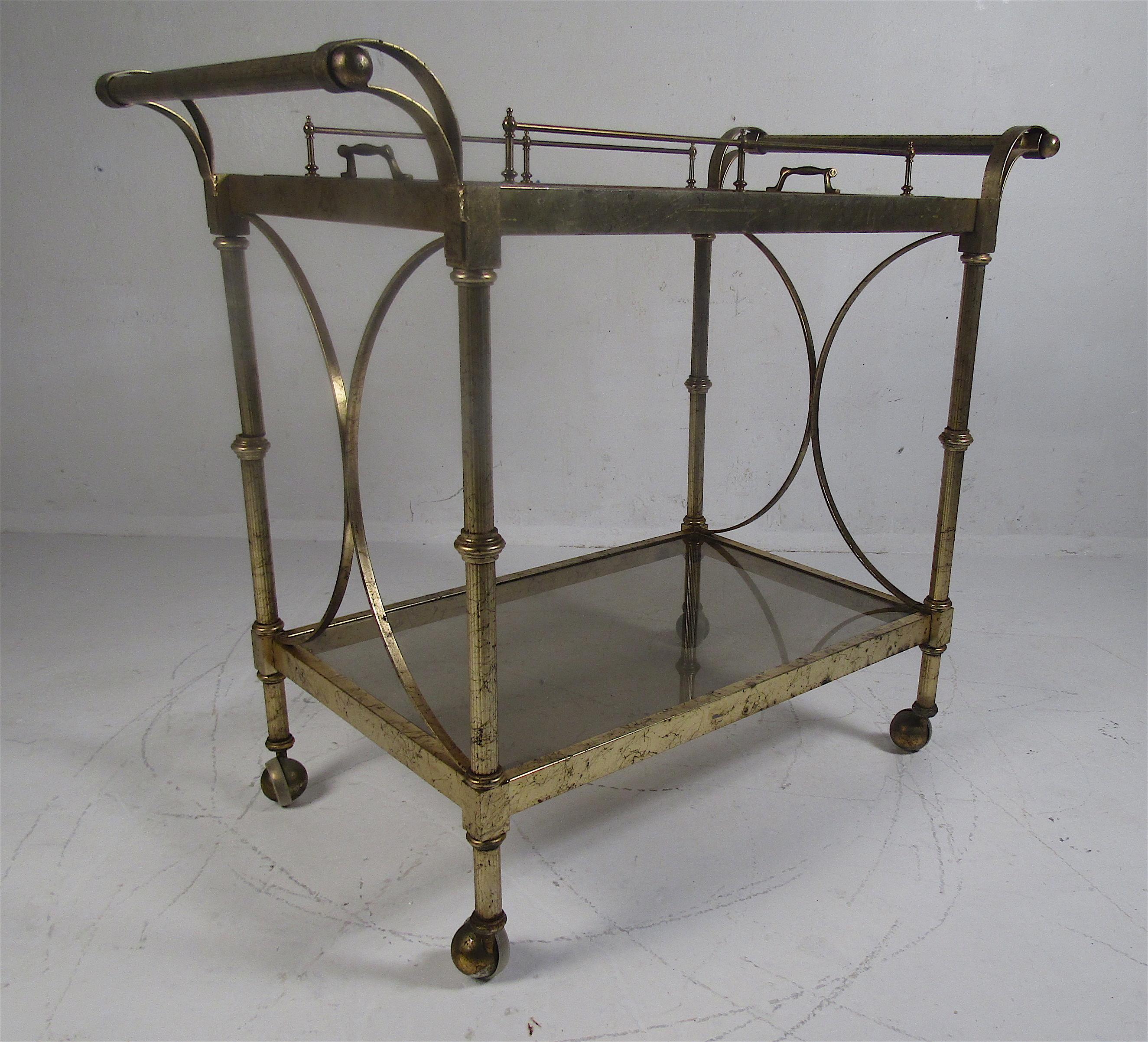 This beautiful vintage modern serving cart features a removable burl and glass tray on the top with brass handles. A wonderful design that is capable of serving guests or functioning as a side table. This Hollywood Regency style cart makes the