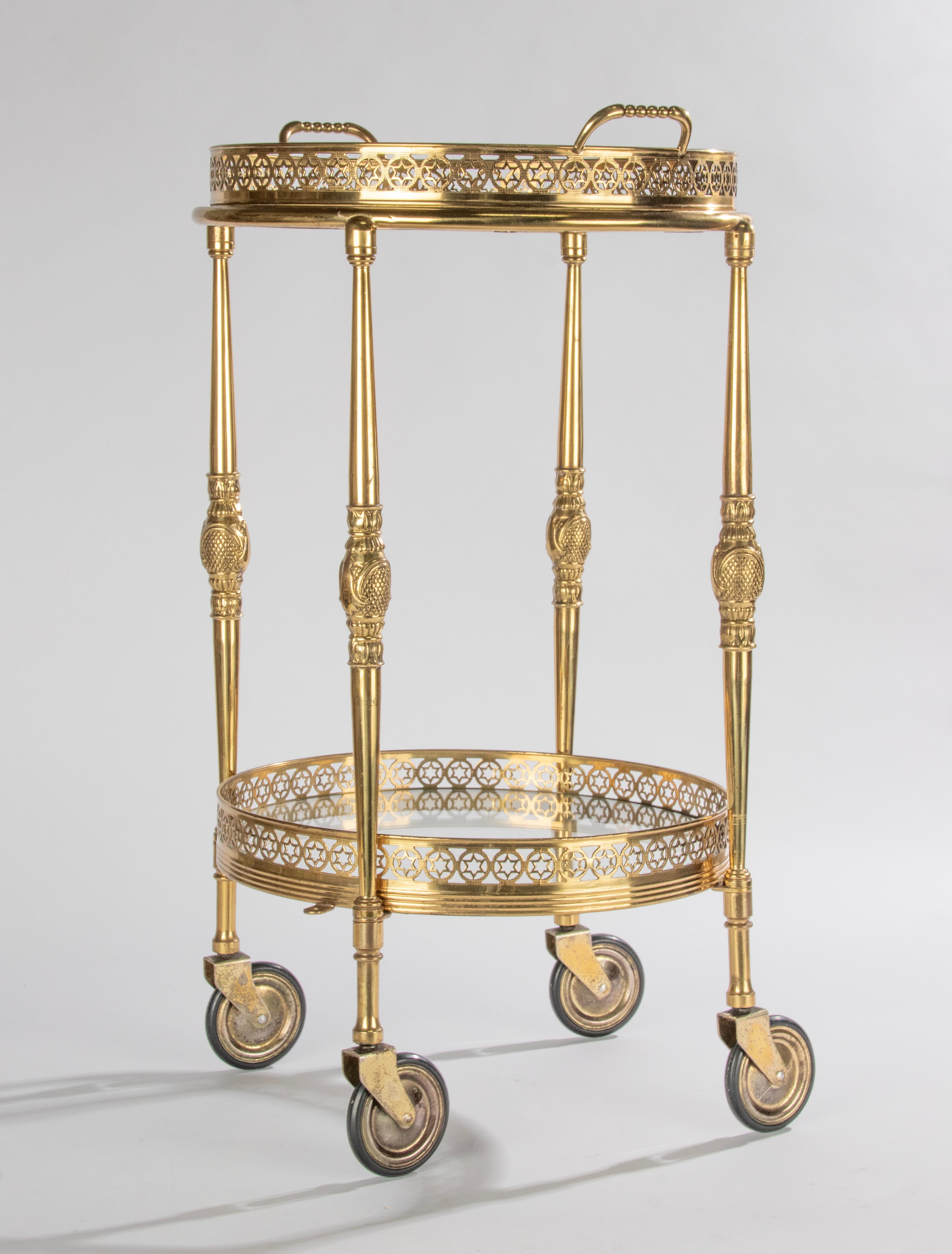 Elegant bar cart with two tiers, in the style of Maison Baguès. The trolley is made of brass colored metal and glass, with beautiful refined details, such as the openwork gallery edges. The top tray is removable and can be used separately. The