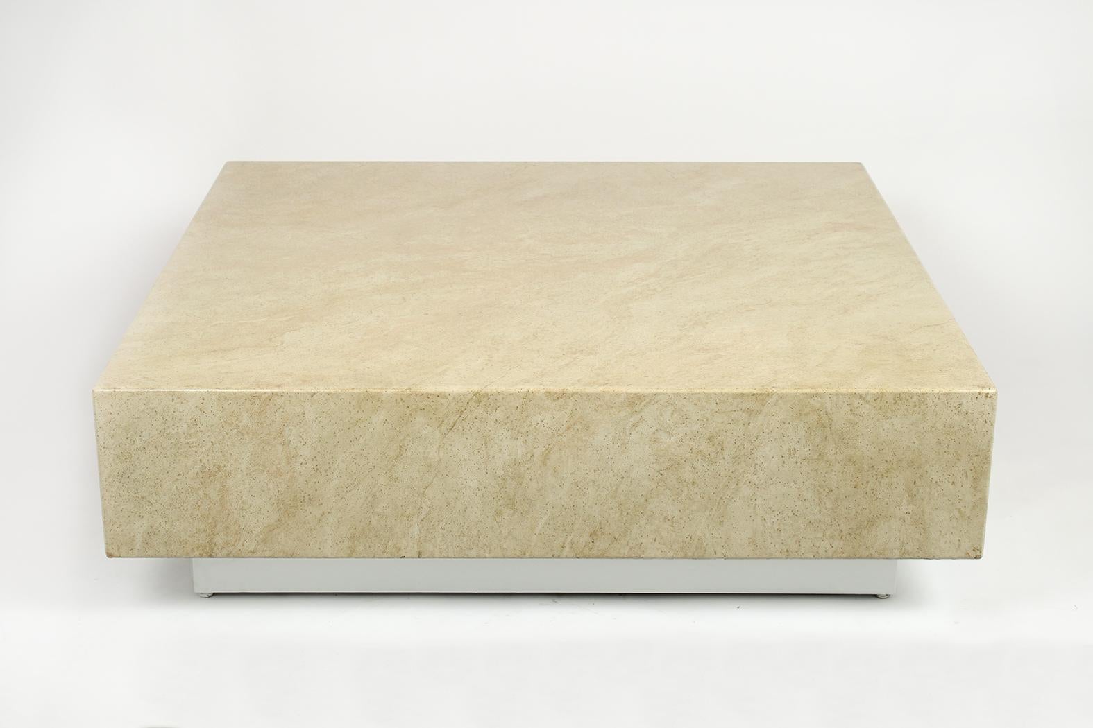 This Mid-Century Modern low coffee table has been restored and is in great condition. It features a large square top with a faux travertine marble design and rests on a four-inch-tall floating base finished in an off white color with a lacquered