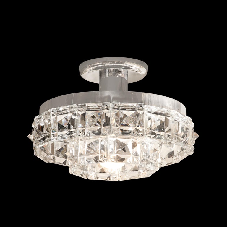 This beautiful and sophisticated Mid-Century Modern chandelier was realized by the esteemed maker Kinkeldey in Austria circa 1960. It features two circular tiers of faceted crystal (resembling oversized cut diamonds) with polishes chrome banding