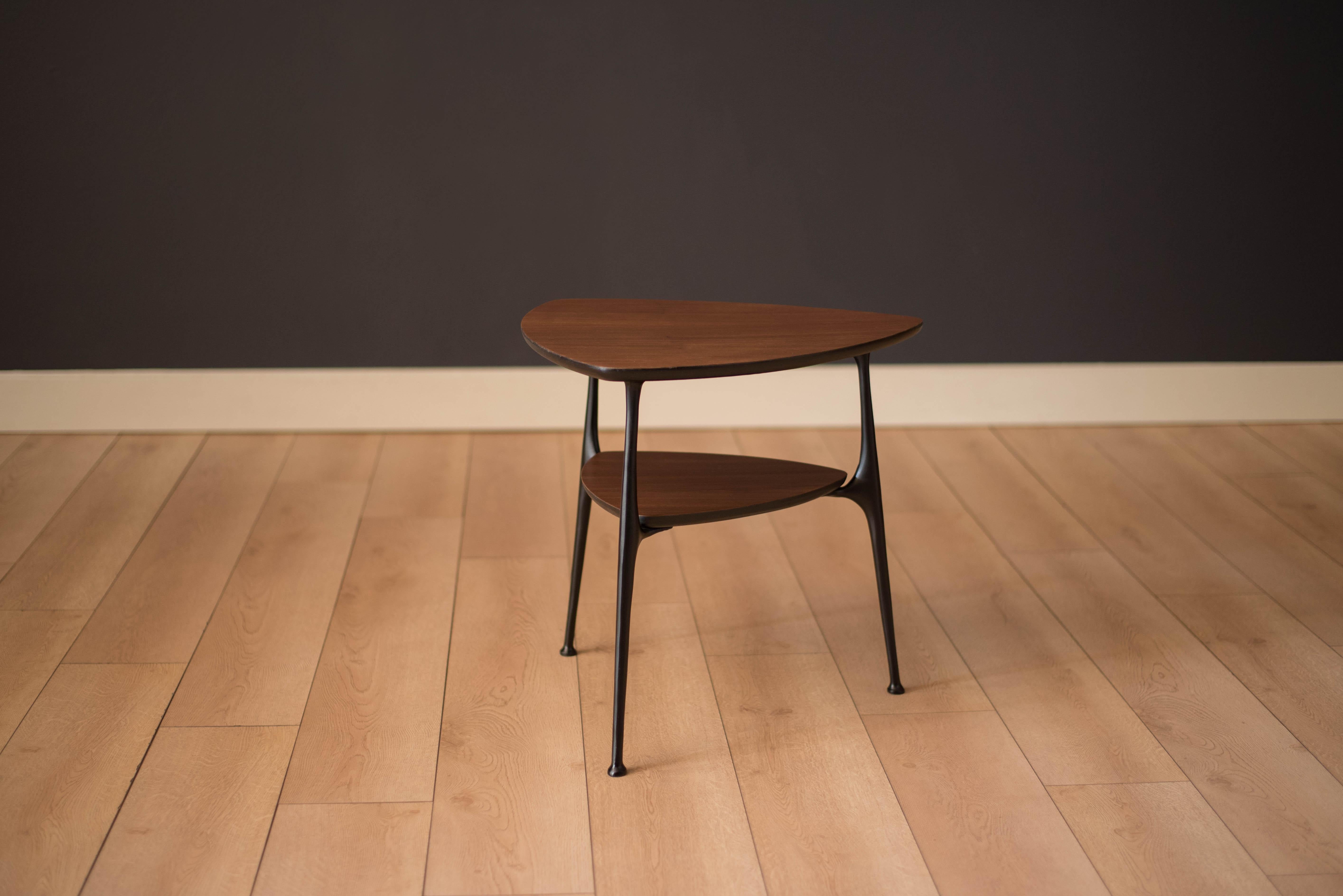 Vintage triangle side table in walnut, circa 1960s. This two-tone piece displays well from all angles and provides an open design that fits in small spaces. Features sturdy contoured cast iron legs and a two-tier walnut top.
 