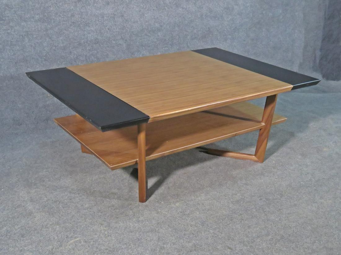 Mid-Century Modern coffee table combining rich woodgrain with black panels in an elegant design. A bottom tier allows for extra storage of magazines or books and makes this table a stylish and functional element of any living room. Please confirm