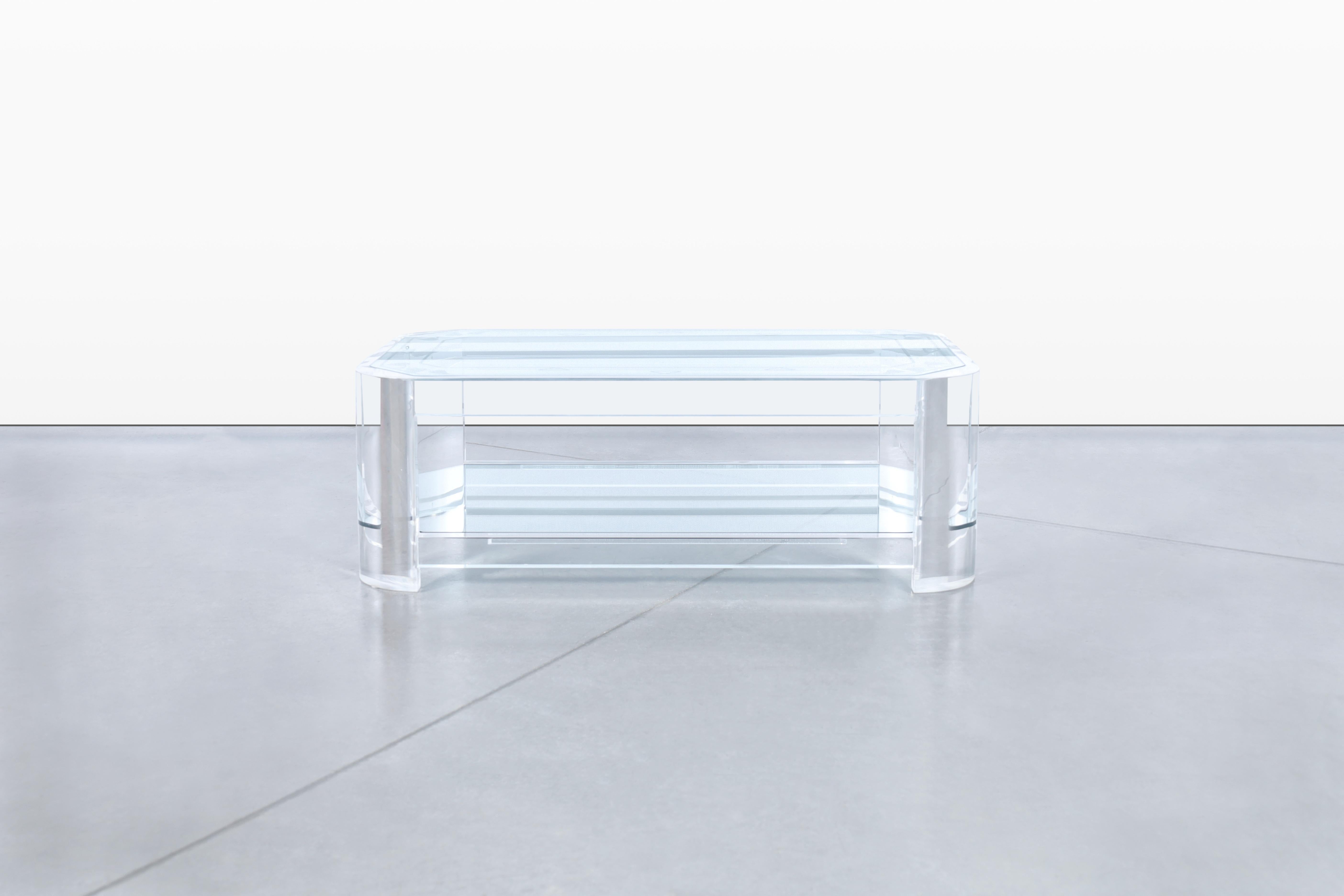 Cette exquise table basse vintage en lucite, fabriquée aux États-Unis vers les années 1980, est une pièce étonnante qui capture parfaitement l'élégance du design du milieu du siècle. La structure à deux niveaux ajoute de la fonctionnalité et crée un